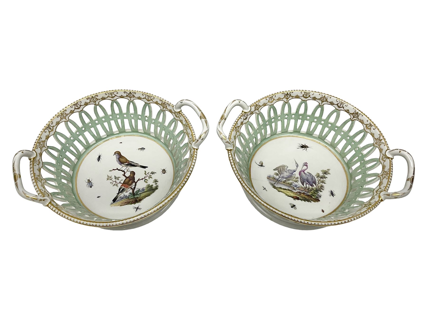 Pair of 19th century German openwork chestnut baskets, with twin handles and scrolling gilt border and star rim, painted to the centre with birds and insects, D22cm 