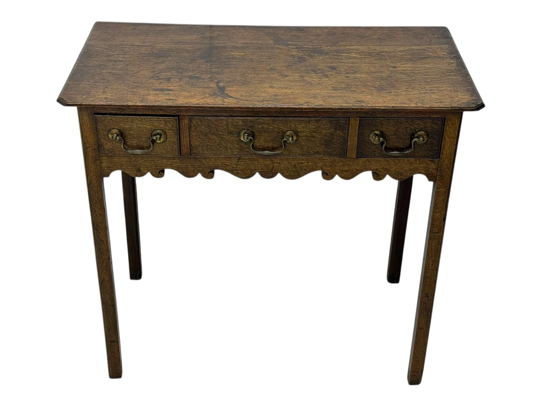 18th century oak lowboy, rectangular moulded top over three frieze drawers with brass swing handles, scalloped apron, on slender square section supports