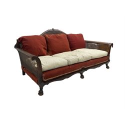 Early 20th century bergère three seat settee, shaped shell carved cresting rail, double caned back and sides, scrolled upright arms and shaped apron carved with shell and foliage, on hairy paw carved feet