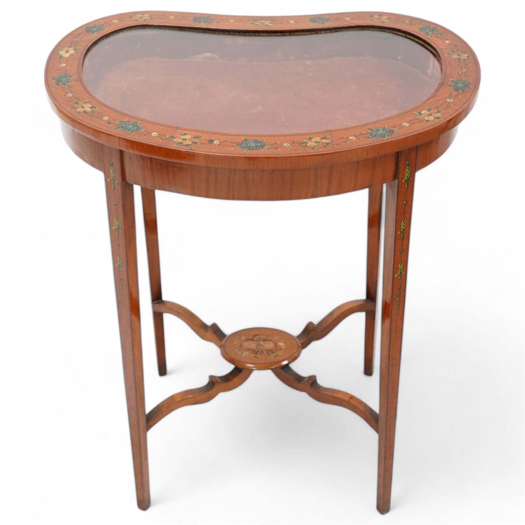 Edwardian satinwood kidney-shaped bijouterie table, hinged lid with glazed panel enclosed by floral painted frame, on square tapering supports decorated with trailing bell flowers, united by shaped stretchers and oval tier painted with ribbon and trumpets 