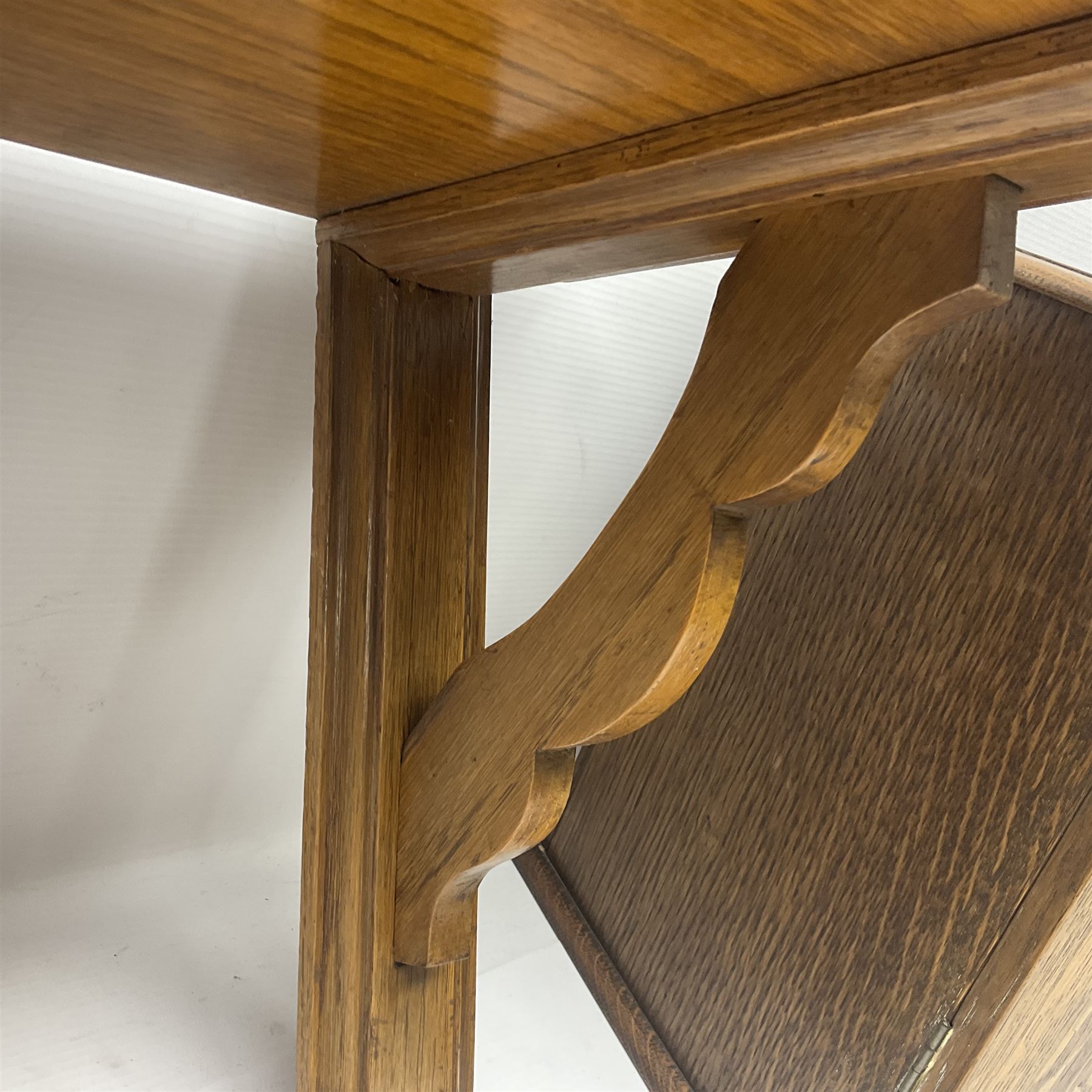 Early 20th century oak smokers cabinet, with brass shield shaped mounts, opening to reveal a compartmentalised interior with three drawers, pipe rack and tobacco jar, together with a small wooden shelf, smokers cabinet H28.5cm