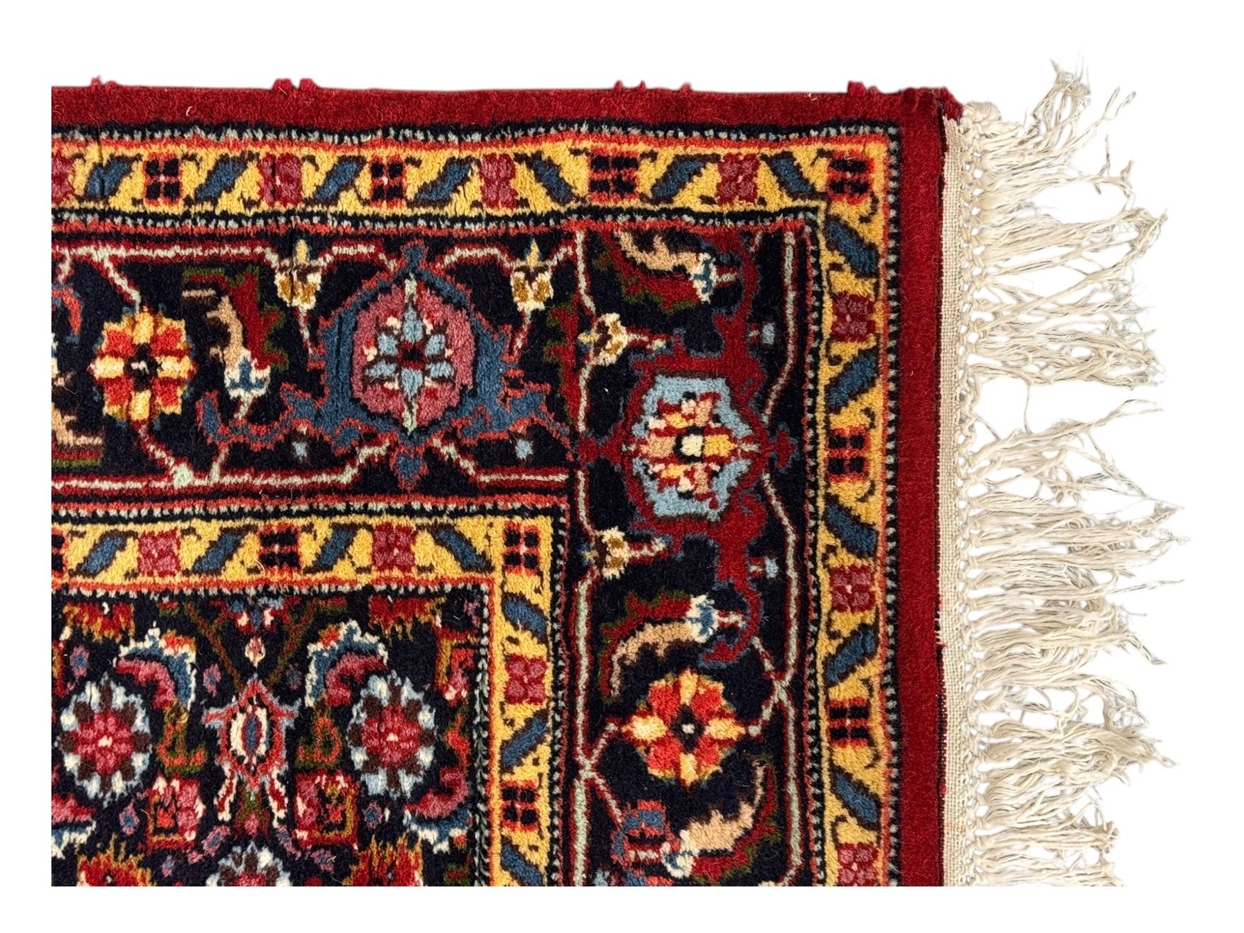Persian crimson ground rug, central light blue lozenge medallion with floral motifs, the densely decorated crimson field filled with repeating flower heads and trailing leafy vines, the black and red border with interlacing foliate patterns and floral cartouches, surrounded by guard stripes