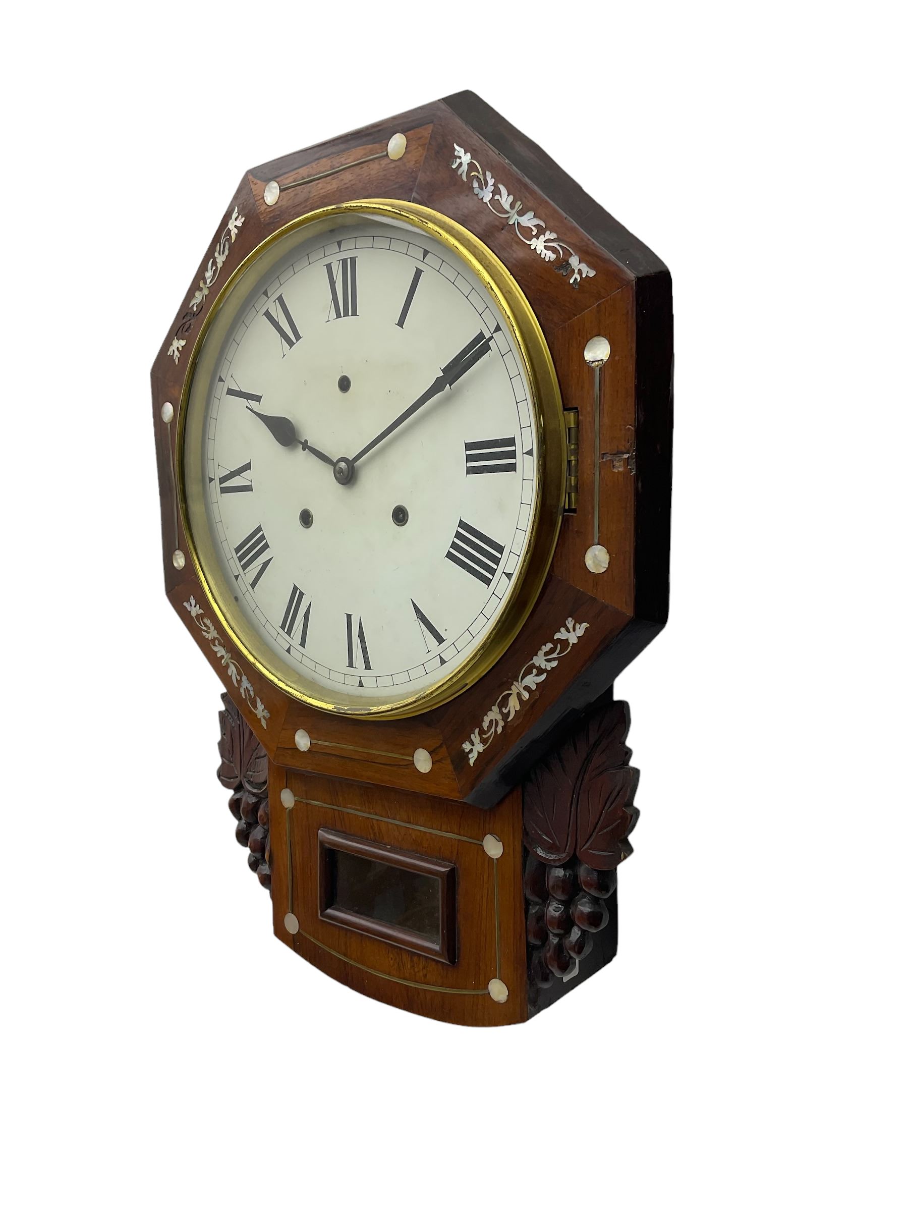 American - late 19th century 8-day mahogany drop dial wall clock, with a hexagonal dial bezel inlaid with mother of pearl, pendulum box with a rectangular viewing glass flanked by carved representations of grape vines, with a painted dial with roman numerals, minute track and steel spade hands within a spun brass bezel, eight day striking movement striking the hours on a gong.   With pendulum & key.