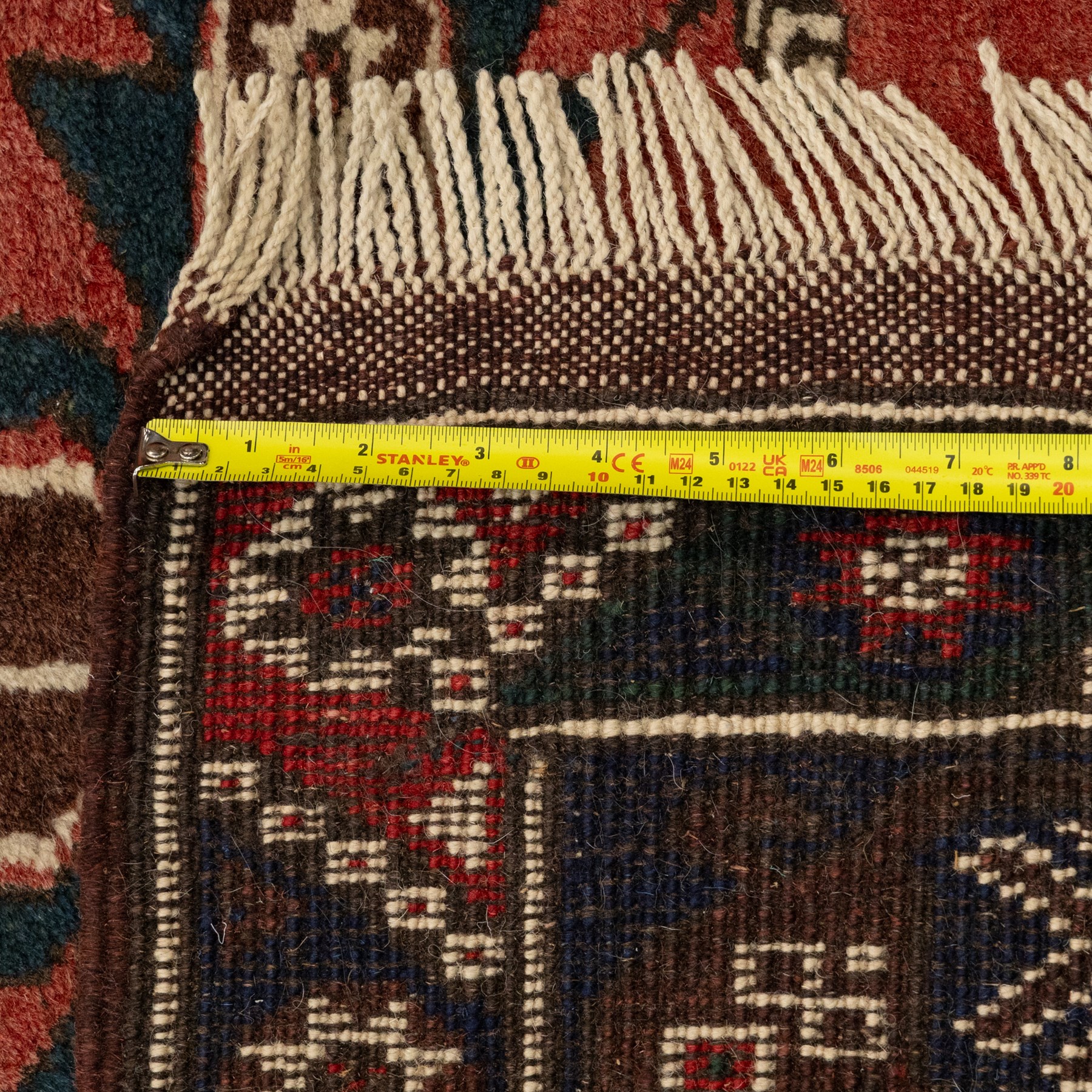 Caucasian Kazak rug, red field with three bold geometric medallions in dark blue, cream and brown, scattered tribal motifs, broad indigo border decorated with stylised hooked forms and multiple narrow patterned borders