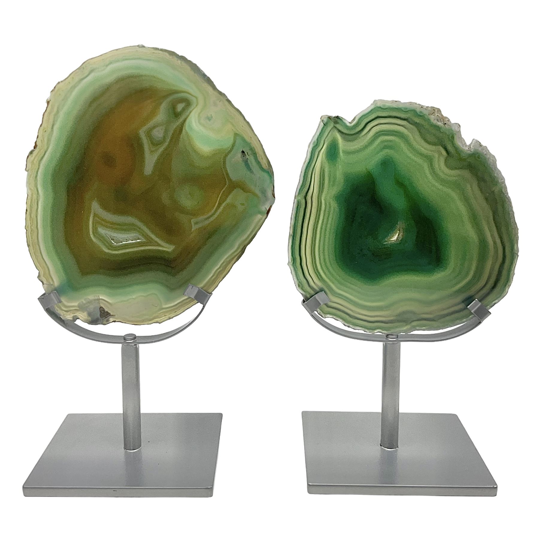 Pair of green agate slices, polished with rough edges, raised upon silvered metal stands, H23cm