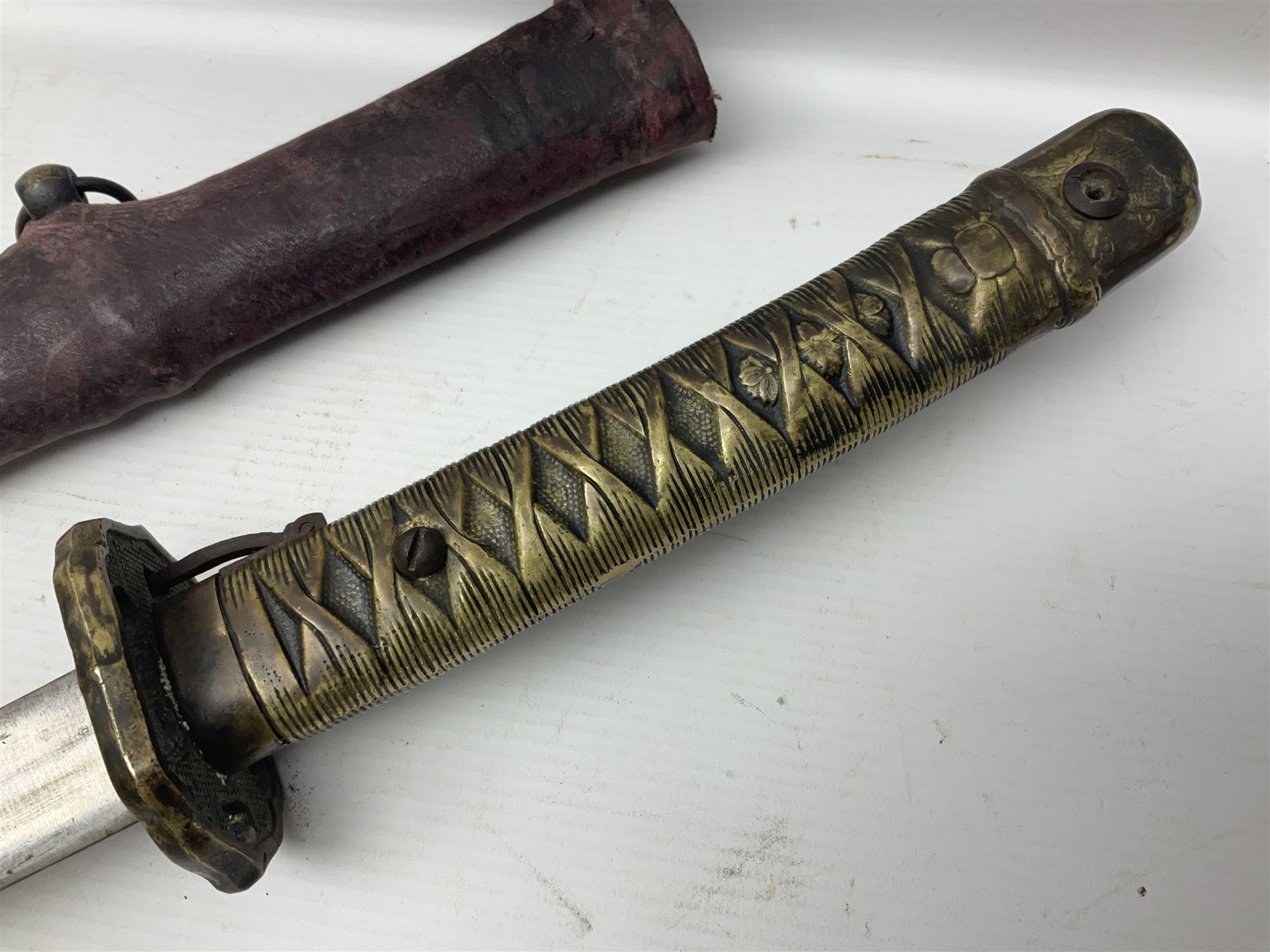 Copy of a WWII Japanese NCO sword, the 65cm slightly curving blade stamped with pseudo Japanese characters and cast brass simulated cord bound grip; in officer's leather bound field scabbard L97cm overall