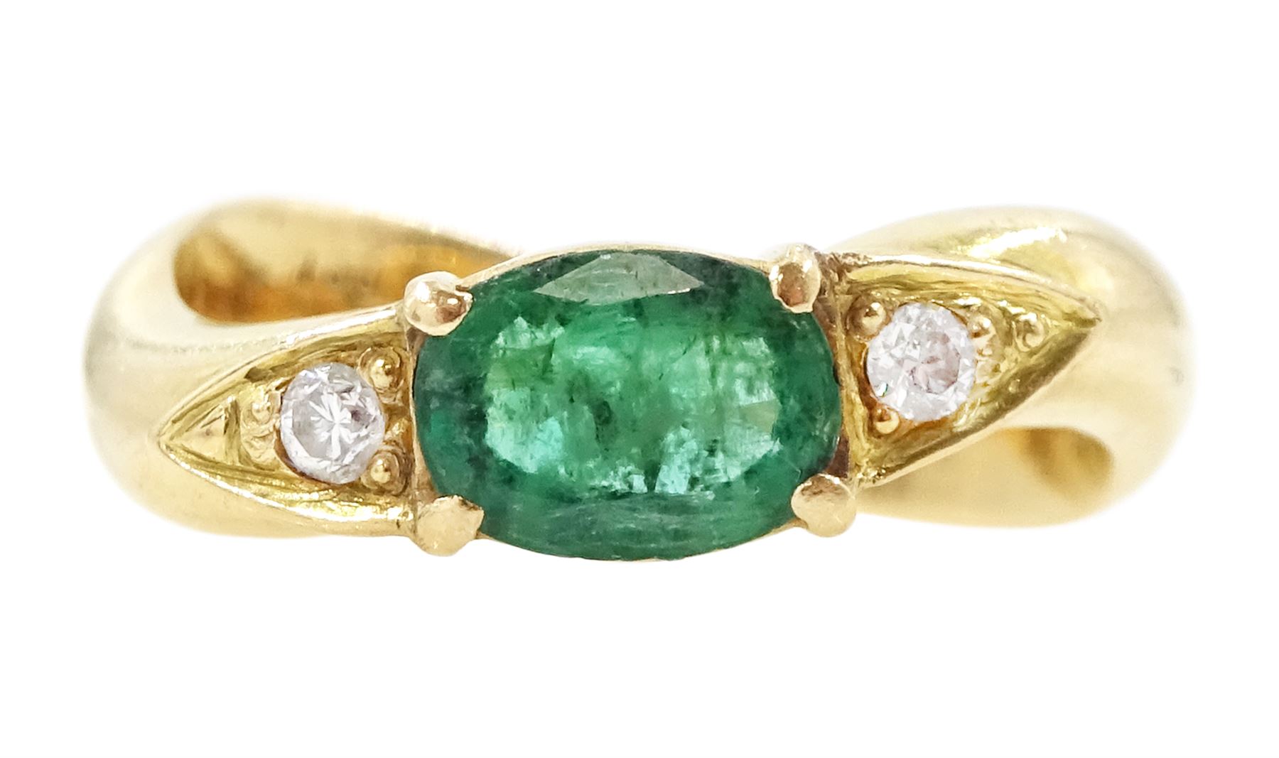 14ct gold emerald and diamond three stone ring, oval cut emerald with a round brilliant cut diamond set either side, to a wave design shank