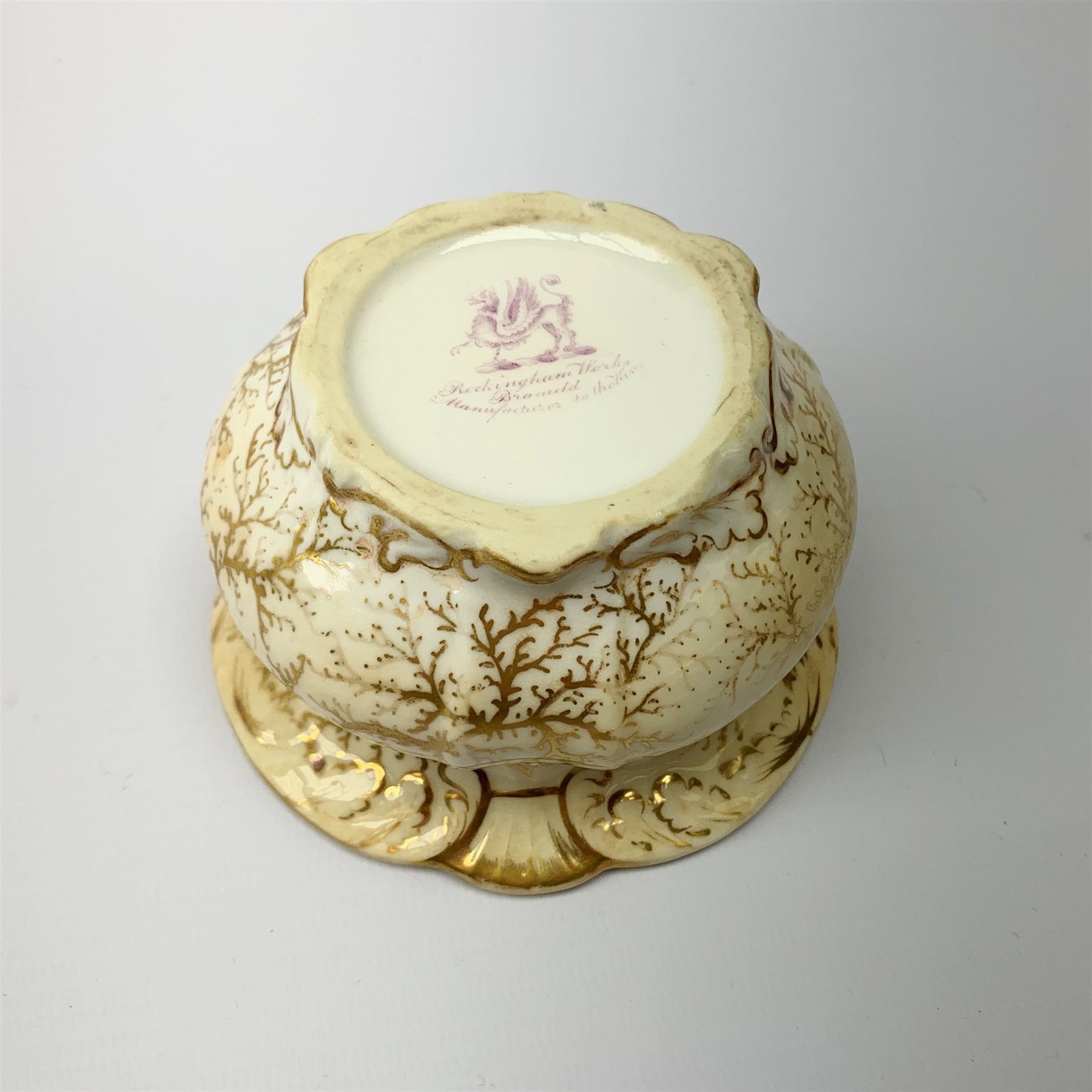 A Rockingham inkwell, with scroll rim, the whole decorated in gilt with a seaweed pattern, with a printed puce mark beneath, D9.5cm. 