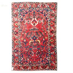 Vintage Persian Heriz crimson ground rug, the field decorated with a central stylised urn ...