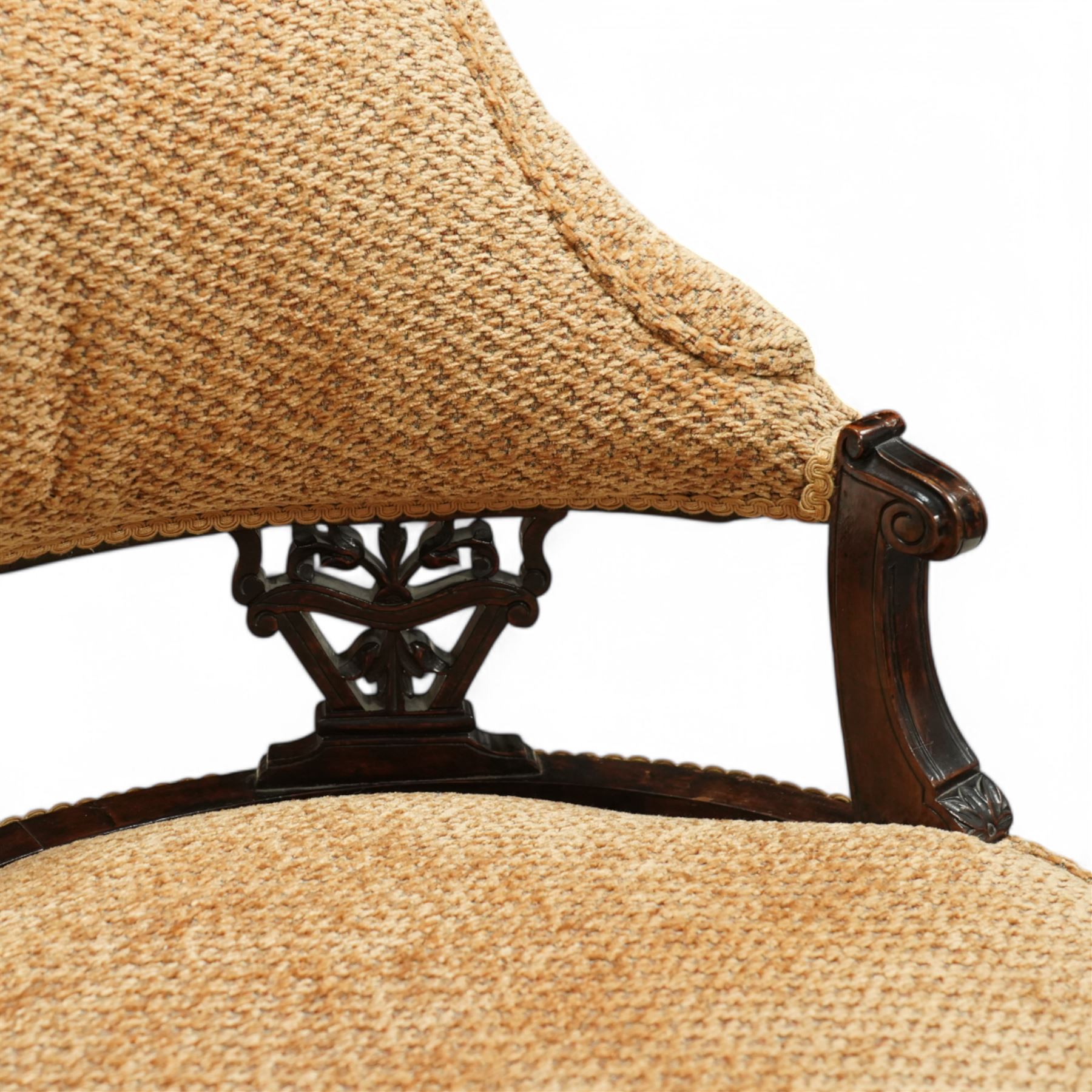 Late Victorian mahogany framed tub shaped chair, curved padded back and overstuffed seat in textured ochre fabric, pierced mahogany back supports with foliate and scroll carving, on turned front legs
