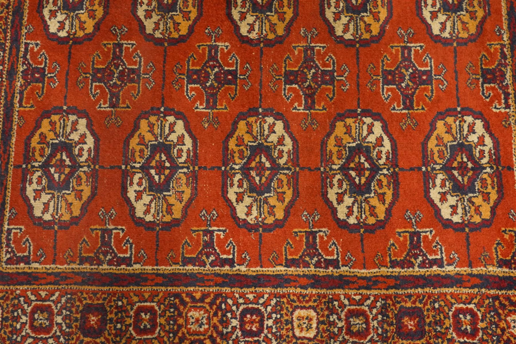 Two hand-knotted rugs, comprising Turkoman Ersari rug and Bokhara rug, Turkoman Ersari hand-knotted rug, terracotta ground with two rows of repeating octagonal guls interspersed with geometric motifs, enclosed by multiple geometric borders, fringed ends, H125cm, W93cm; Bokhara hand-knotted rug, madder red ground with three rows of repeating Tekke guls interspersed with geometric motifs, enclosed by multiple stylised floral and geometric borders, fringed ends, H188cm, W126cm