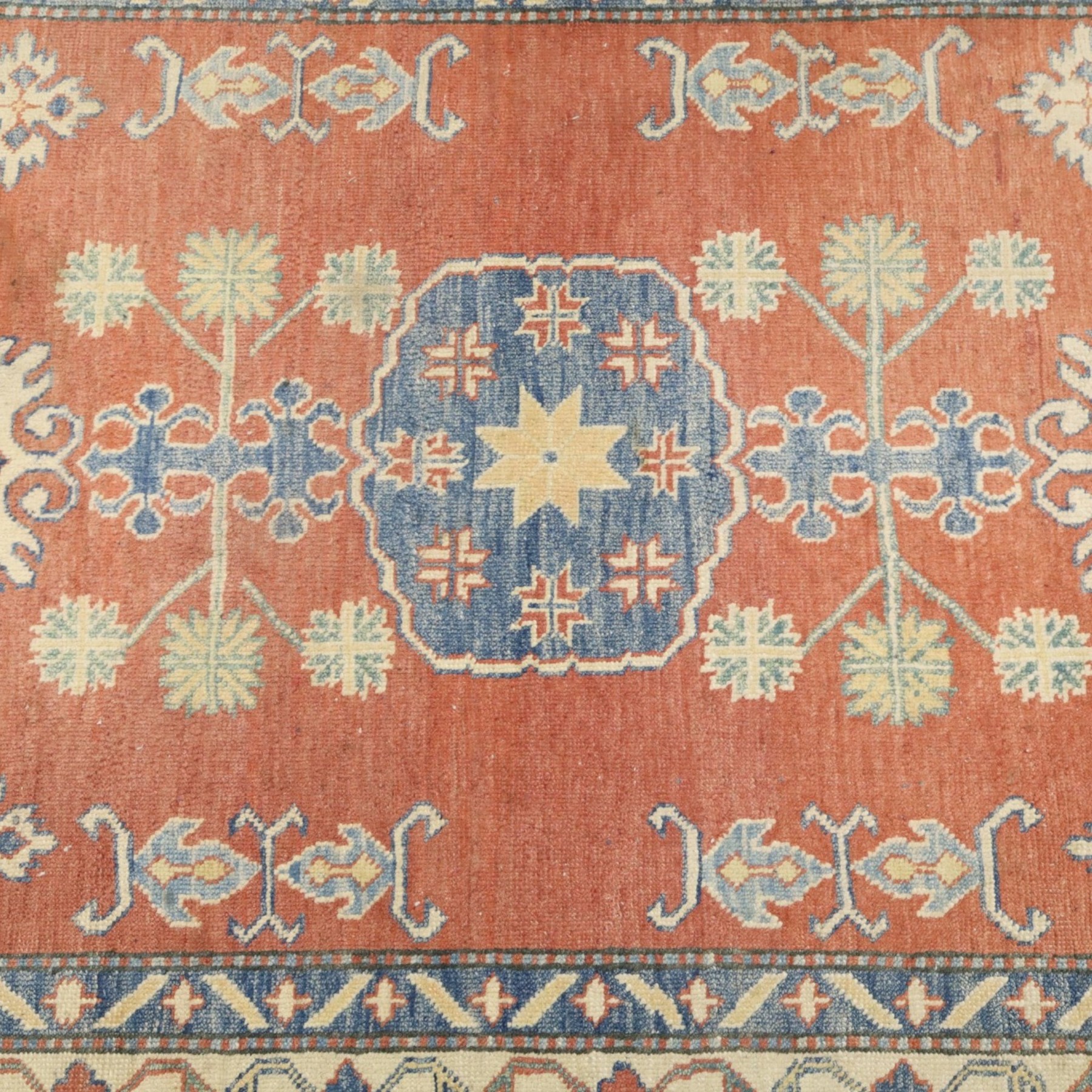 Persian Kazak vermillion ground rug, decorated with a foliate pole medallion with surrounding geometric and plant motifs, the guard bands with repeating floral and geometric design