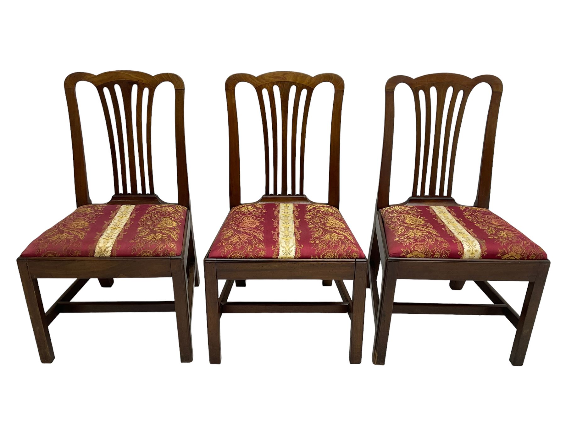 Set of six (5+1) George III mahogany dining chairs, shaped cresting rail over pierced and flared splat, drop-in seat upholstered in crimson and ivory floral patterned fabric, raised on chamfered square supports united by H-stretcher
