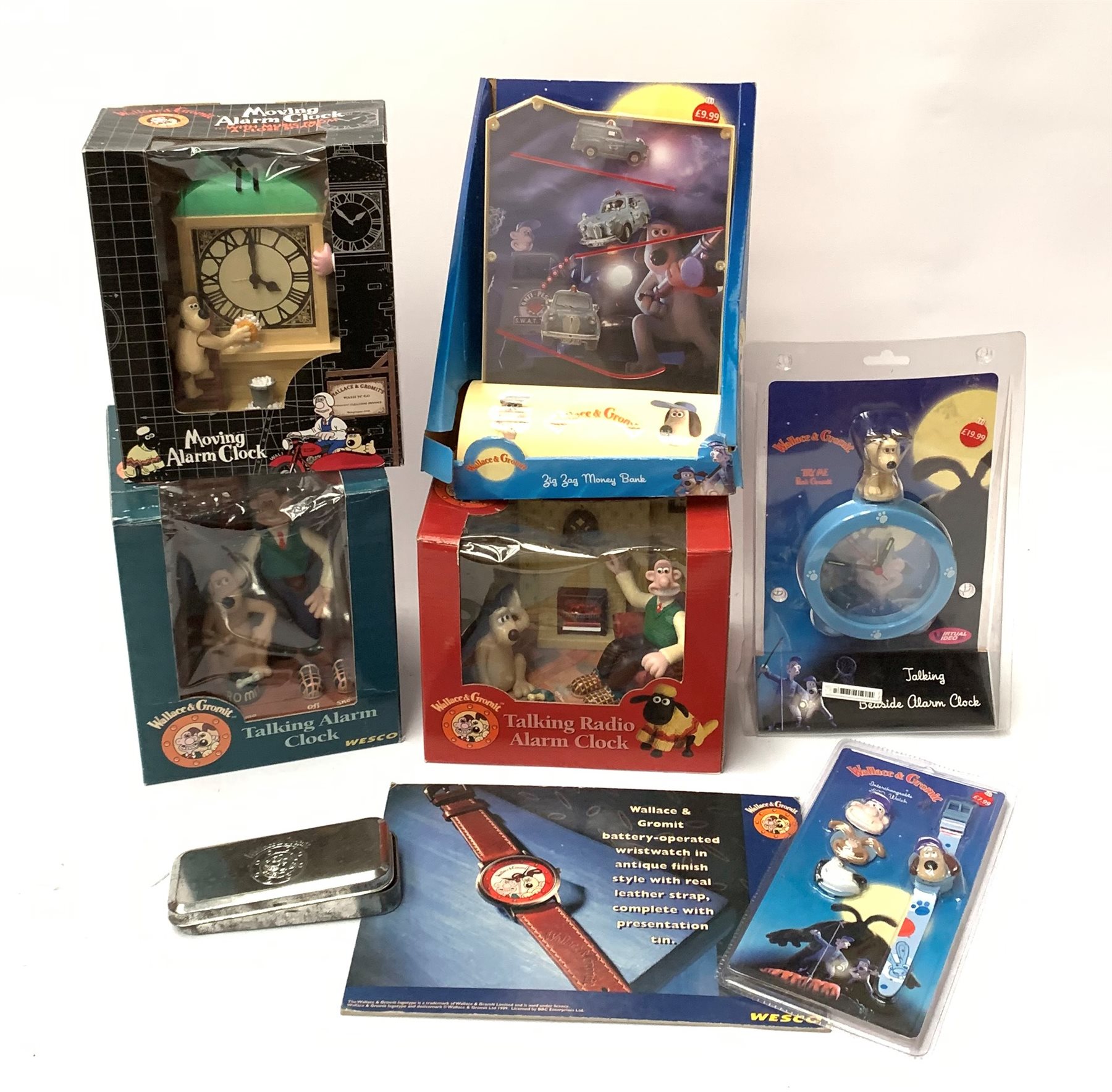  Wallace & Gromit Wesco promotional items - three talking alarm clocks, another with moving parts playing music from A Close Shave, wristwatch in presentation tin with shop counter-top easel advertising card,  wristwatch with interchangeable character head cover and Zig-Zag Money Bank, all in original packaging (7)  