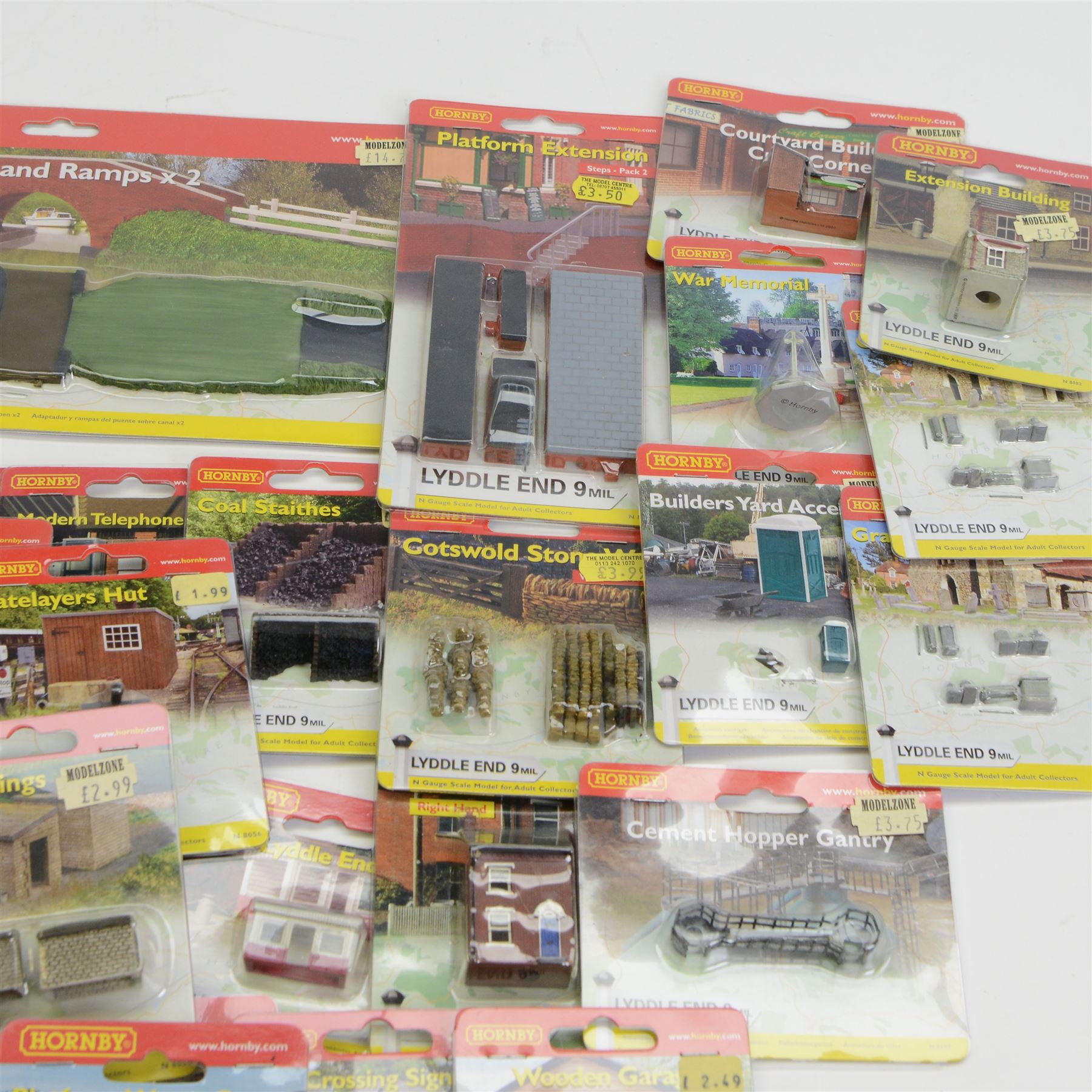 Forty-six Hornby N Gauge Lyddle End model railway trackside buildings and accessories, including N8574 Canal Bridge Adapter and Ramps, N8724 Castle Ruins Walling x 3, N8069 Tractors, N8018 Cotswold Stone Wall and N8096 Low Relief Terrace, all carded