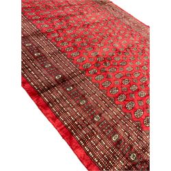 Persian Bokhara crimson ground carpet, the field decorated with repeating Gul motifs and lozenges, the multi-band geometric border with stylised plant motifs, two additional bands at the ends with geometric lozenges