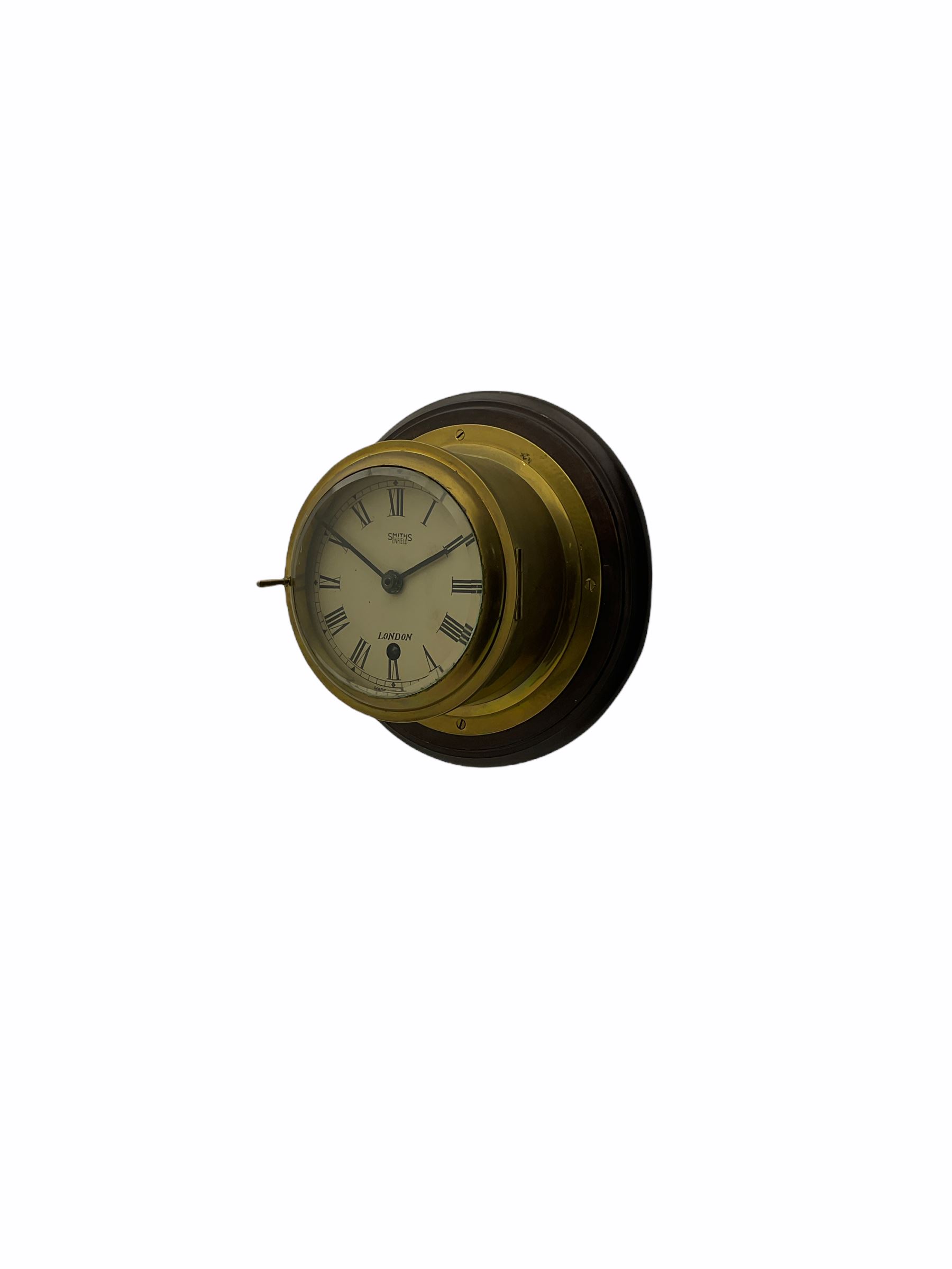 20th century brass cased bulkhead clock mounted on a circular mahogany