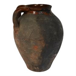 Three early 20th century Spanish part glazed terracotta storage vessels, the first example of bellied form with rounded base and twin loop handles, H24cm, the second of baluster for with close set loop handles, H30cm, and the third smaller also of baluster form with single loop handle, H24cm