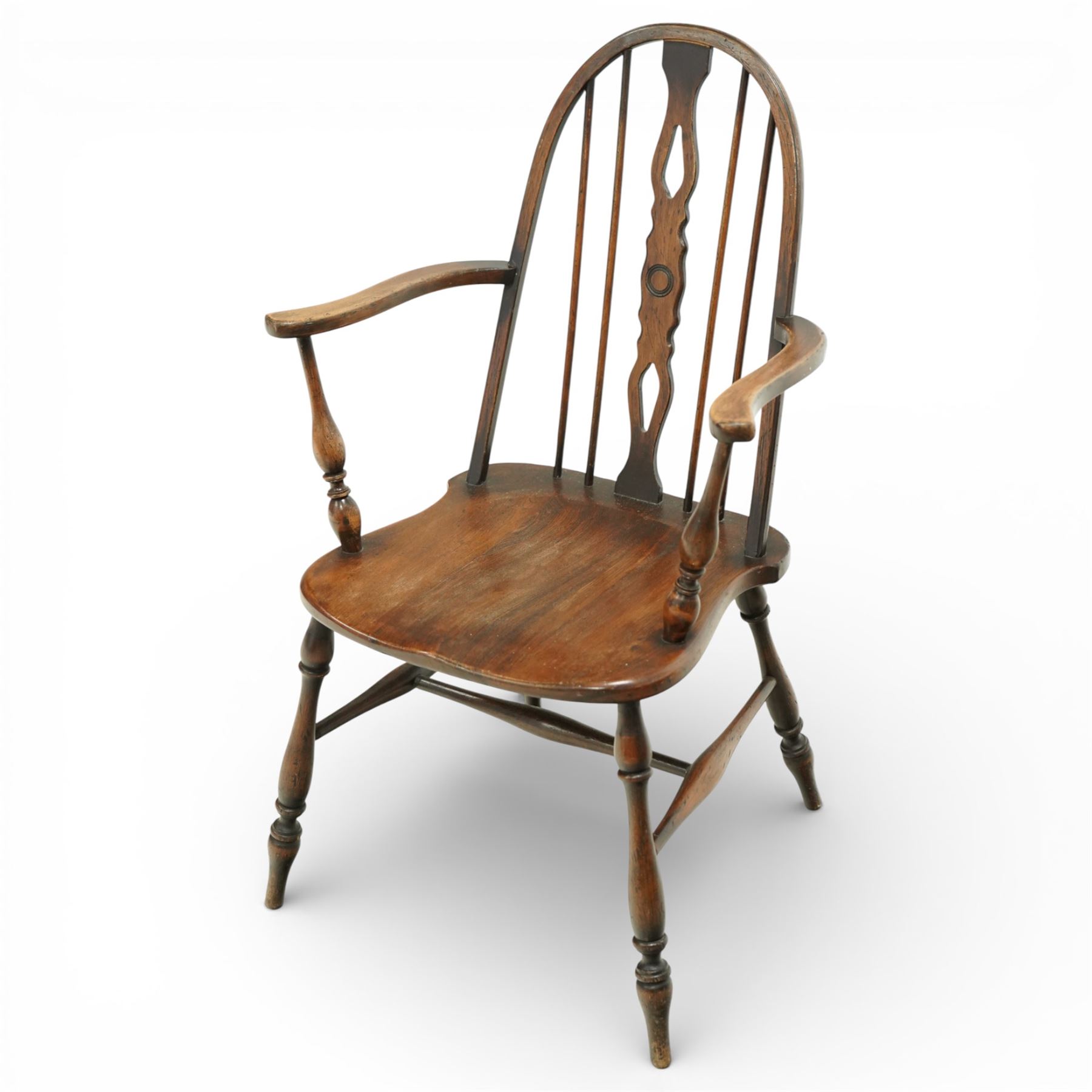 Early 20th century Windsor armchair, the arched hoop back enclosing a pierced and shaped splat flanked by turned spindles, above a shaped elm seat and outswept arms on turned supports, raised on turned legs united by an H stretcher
