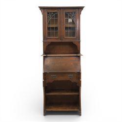 Arts & Crafts oak bureau bookcase, projecting cornice with leaded and glazed upper cabinet, the lower section with fall front section revealing a fitted interior, above shaped lower shelving 