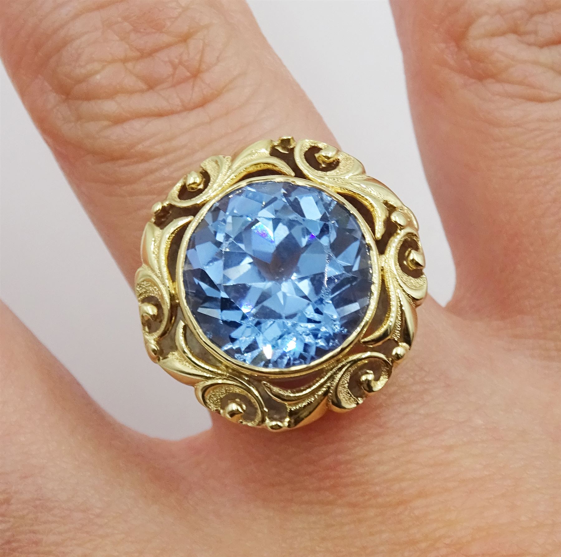 18ct gold single stone round synthetic blue spinel ring, with pierced leaf border