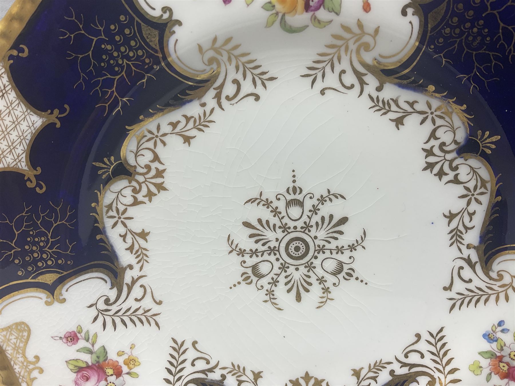 Coalport cobalt blue batwing pattern tea wares, decorated with finely enamelled floral sprays within gilt reserves, comprising teacup trio, coffee can and saucer and other cup and saucer, twin handled cake plate, milk jug and open sucrier, and circular plate retailed by T. Goode & Co London, pattern no Y2665,  all with green Coalport AD 1750 marks beneath, largest W26cm (11)