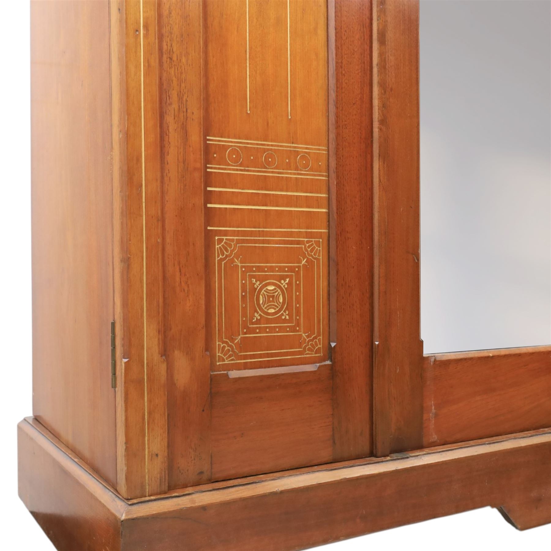 Aesthetic Movement walnut parcel gilt wardrobe, the crenellated top, above central mirrored door opening to reveal hanging space, four opened and two closed draws