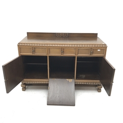 E. Gomme Ltd of High Wycombe oak sideboard, raised carved back, moulded top, three drawers above two cupboards flanking single fall front unit, turned supports joined by stretchers, W150cm, H101cm, D57cm