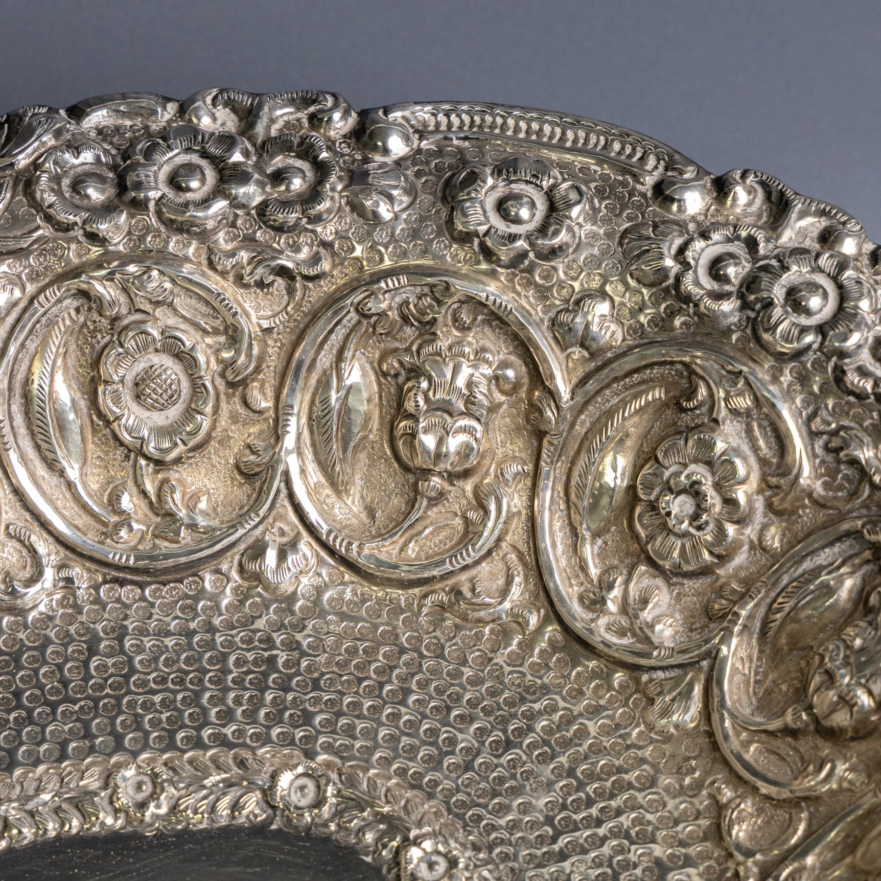 Late 19th/early 20th century continental silver serving bowl, of oval form, profusely embossed with scrolling floral and foliate decoration, with hammered finish to interior