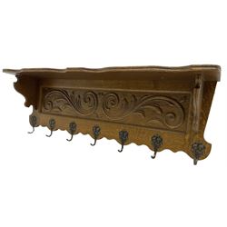 Oak wall hanging coat rack, shape lintel over panelled back carved with foliate S-scrolls, fitted with seven hooks