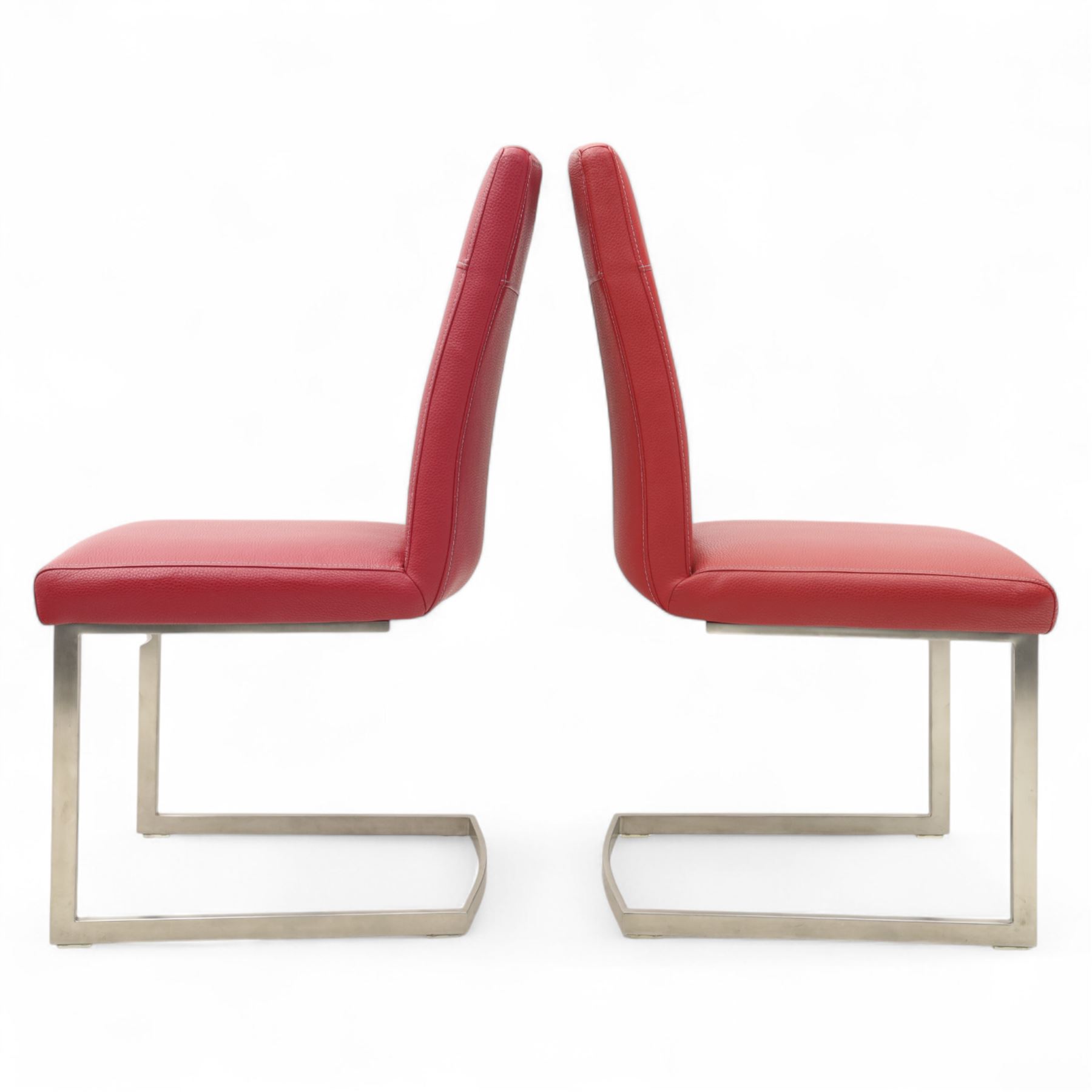 Set of seven contemporary style dining chairs, each with a high padded back and seat upholstered in faux leather on brushed steel sled bases  