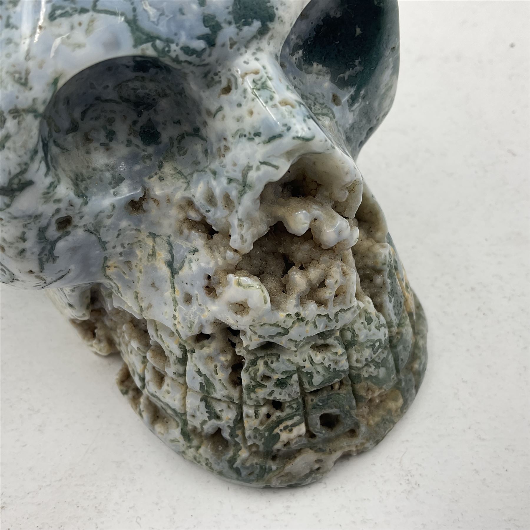 Carving of a skull in moss agate, H9cm, L12cm 