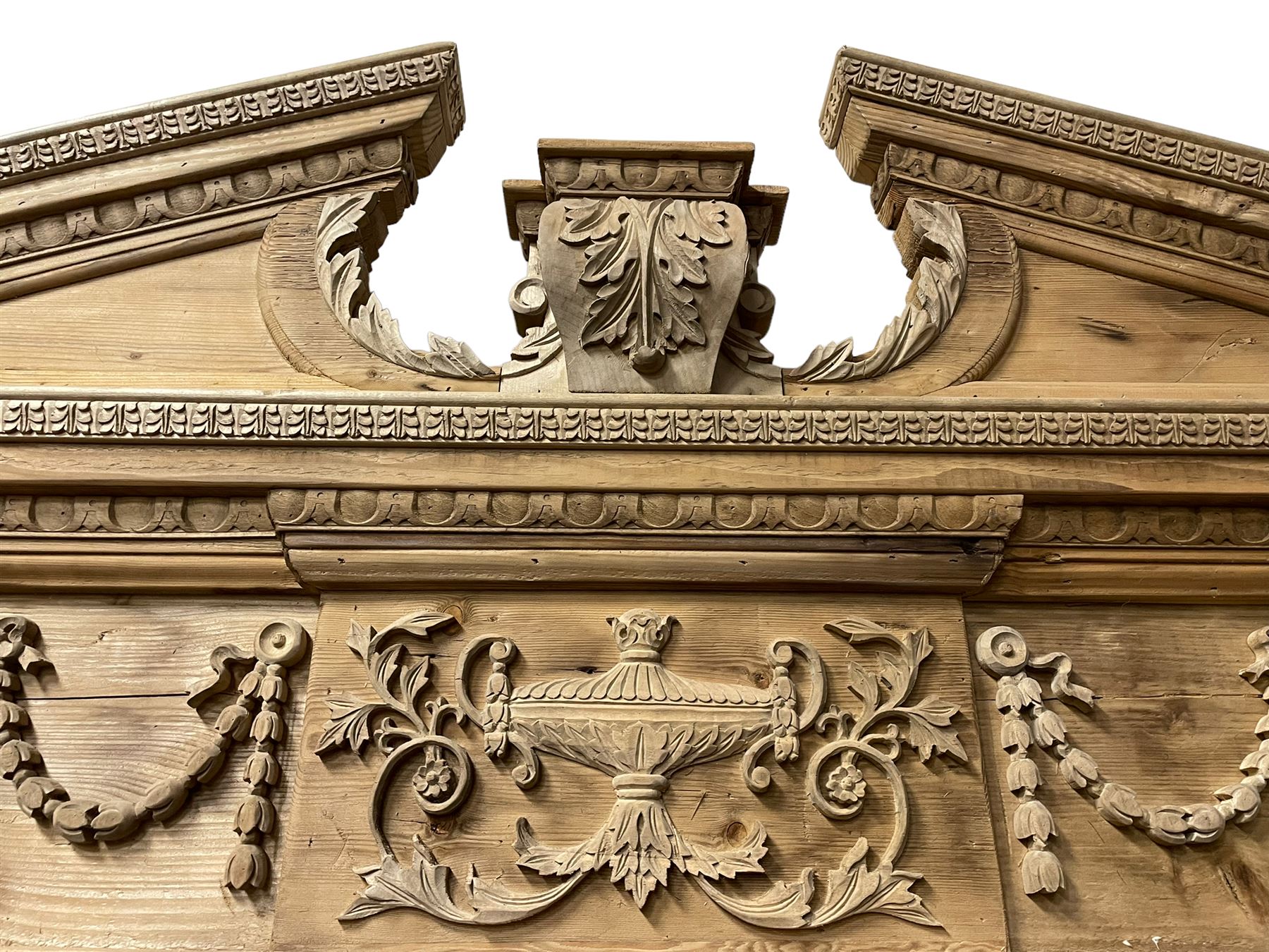 Large Adams design pine frame mirror, sloped broken arch pediment with central acanthus leaf carving, the frieze decorated with bell flower garlands and central kylix vase motif, large plain mirror plate flanked by panelled sides with egg and dart mouldings and reeded slip mouldings, on plinth base