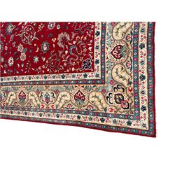 Persian crimson ground carpet, the central foliate pole medallion within a field of palmettes and scrolling branches with matching spandrels, multi-band ivory border decorated with repeating plant motifs