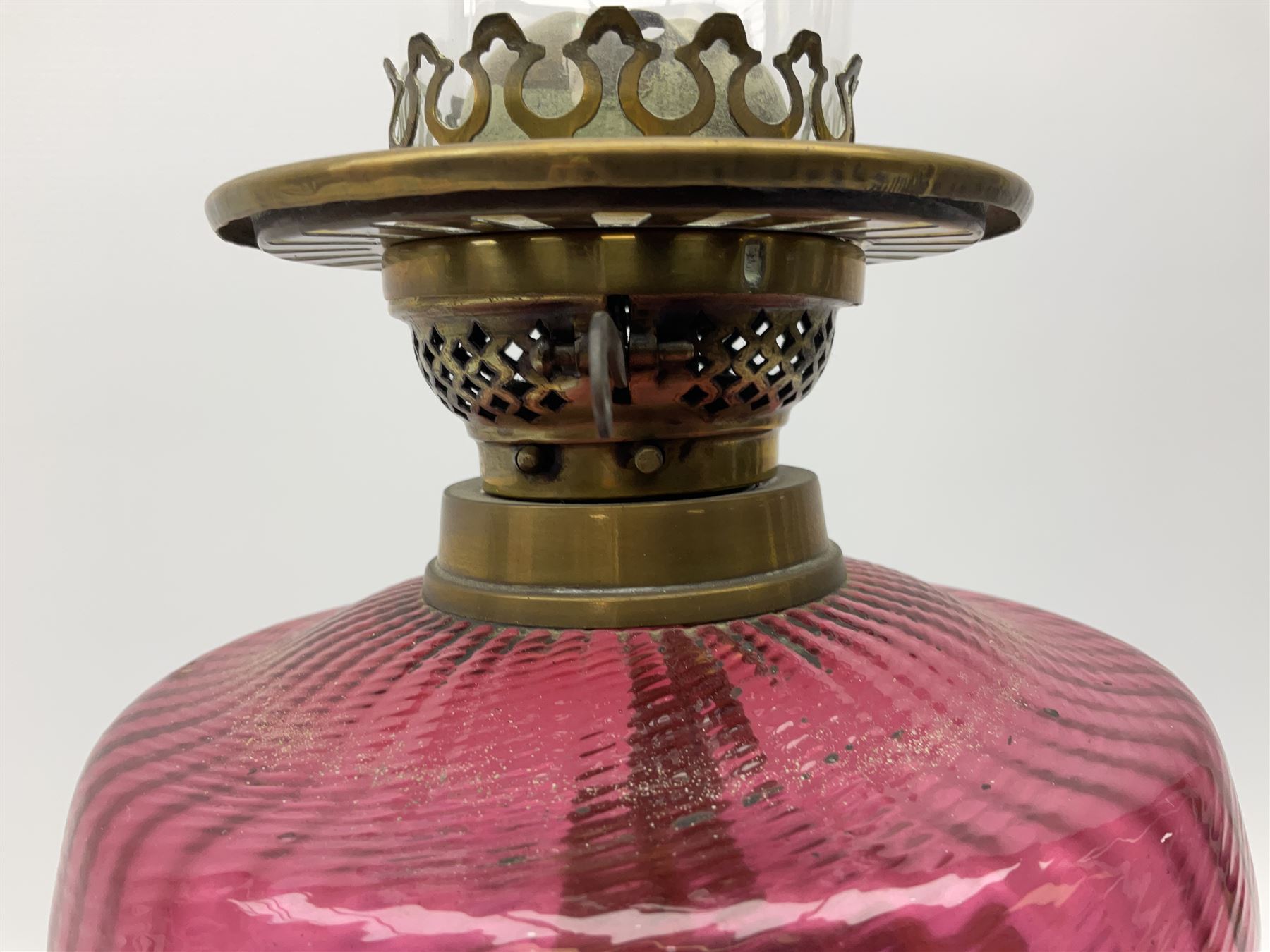 Victorian table standing oil lamp, brass fittings, cranberry glass reservoir, brass column on black enamelled ceramic base, with a frosted glass shade and clear glass chimney, H68cm