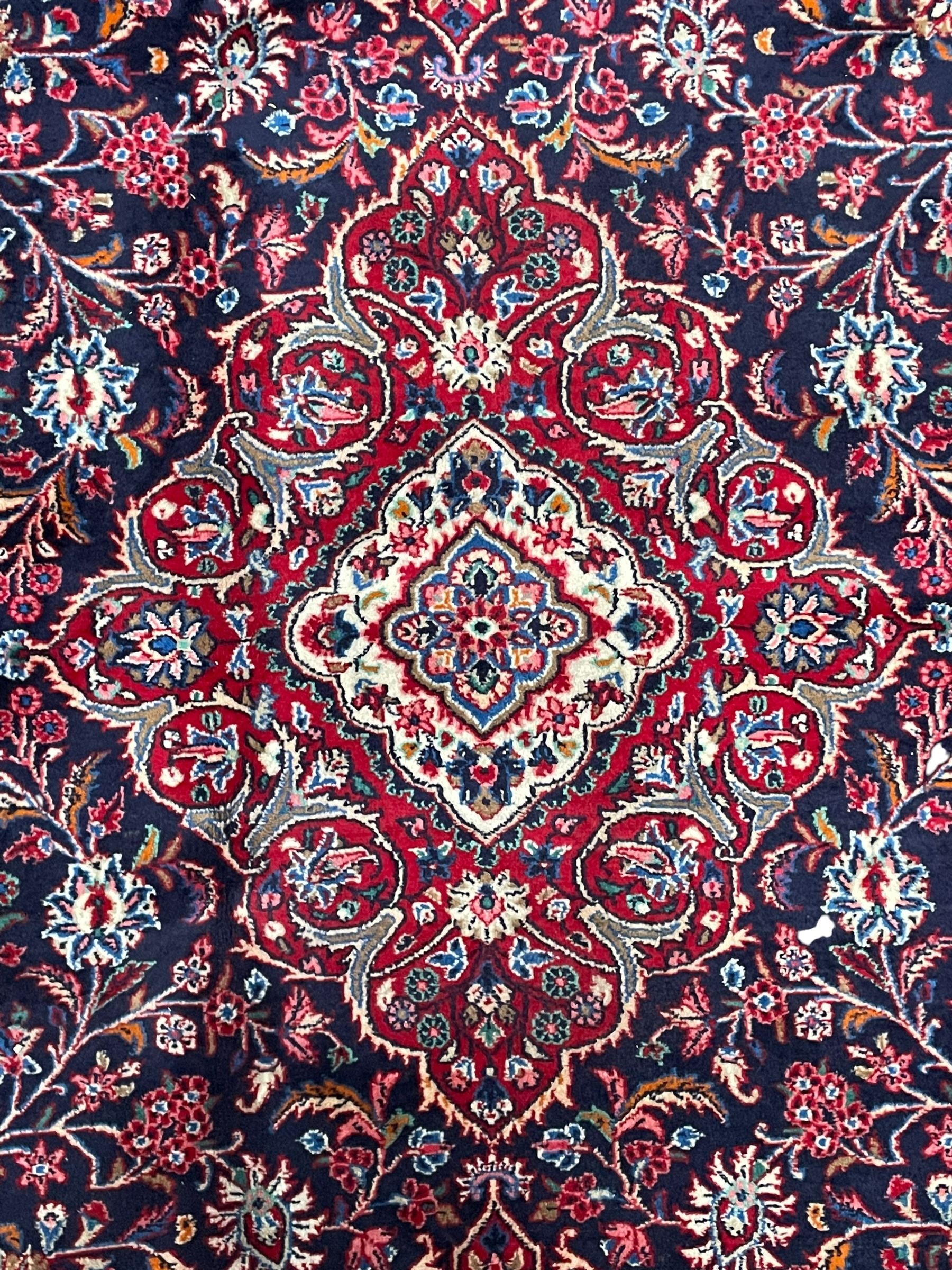 Persian Hamadan indigo ground carpet, the field decorated with central rectangle and outer band, overall floral pattern with cusped central medallion and surrounding leafy branches with palmettes, the border with scrolling branches decorated with further palmettes, within floral pattern guard stripes