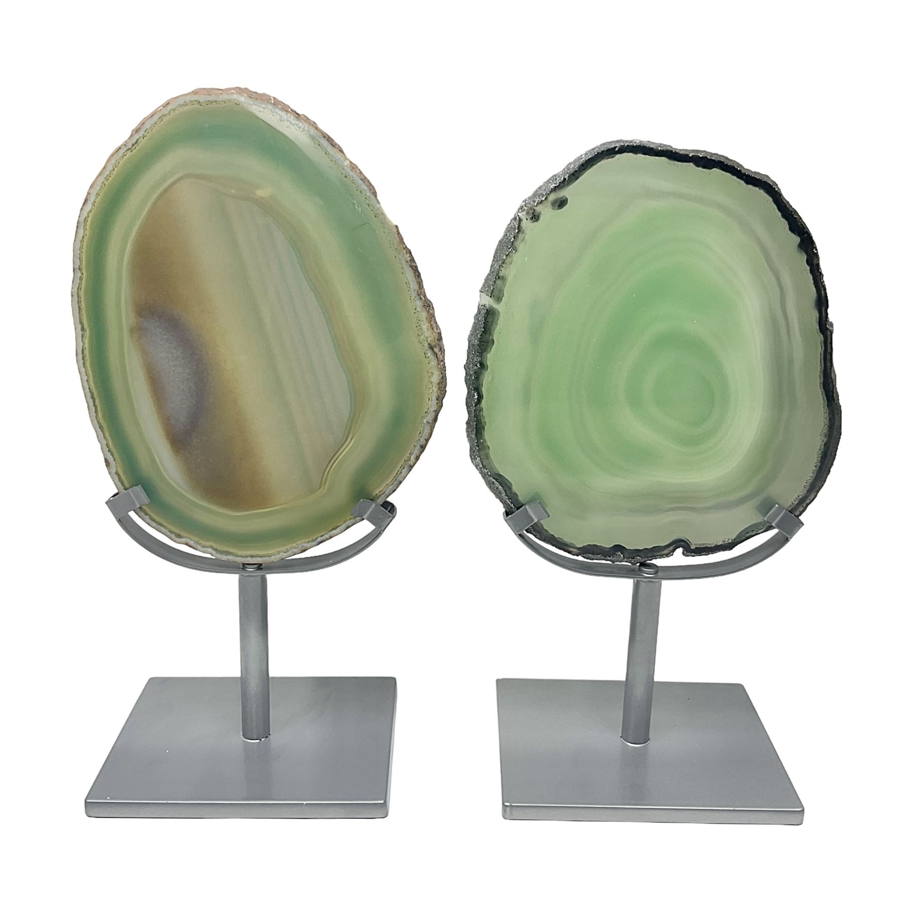 Pair of green agate slices, polished with rough edges raised upon silvered metal stands, H19cm