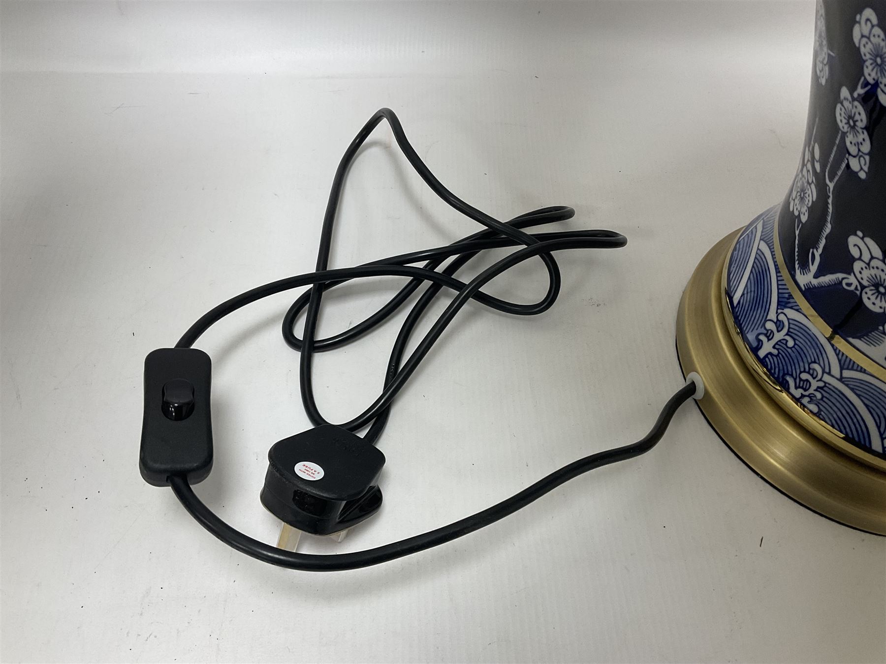 Pair of blue and white table lamps, each of baluster form, decorated with prunus blossom, within stylised borders, raised upon circular gilt base, excluding fittings H48cm