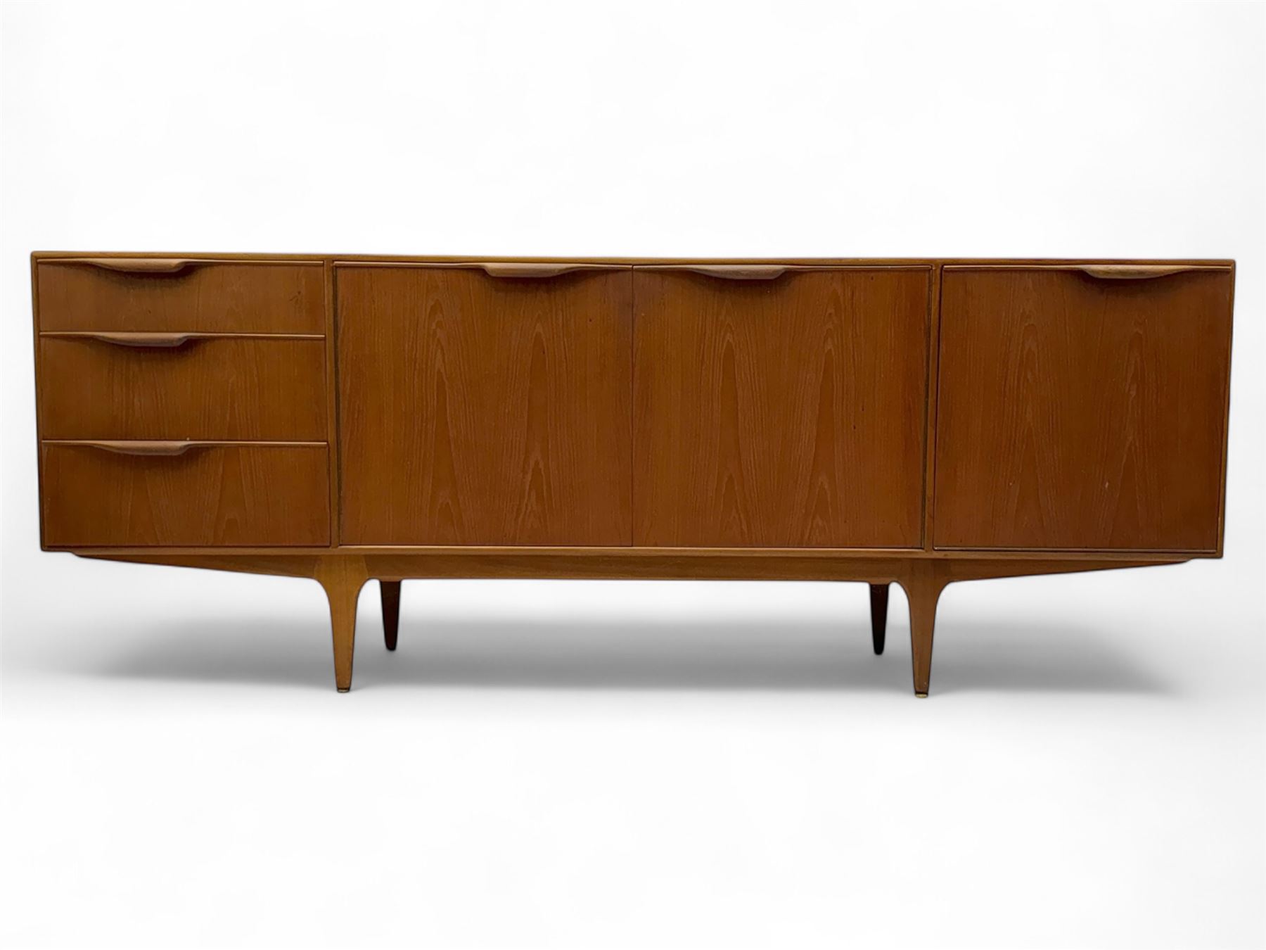 Tom Robertson for AH McIntosh & Co of Kirkaldy - mid-20th century teak 'Dunvegan' sideboard, with three graduating drawers fitted cutlery divider, three cupboards one fall front each with recessed sculptural handles, raised on shaped and tapering supports