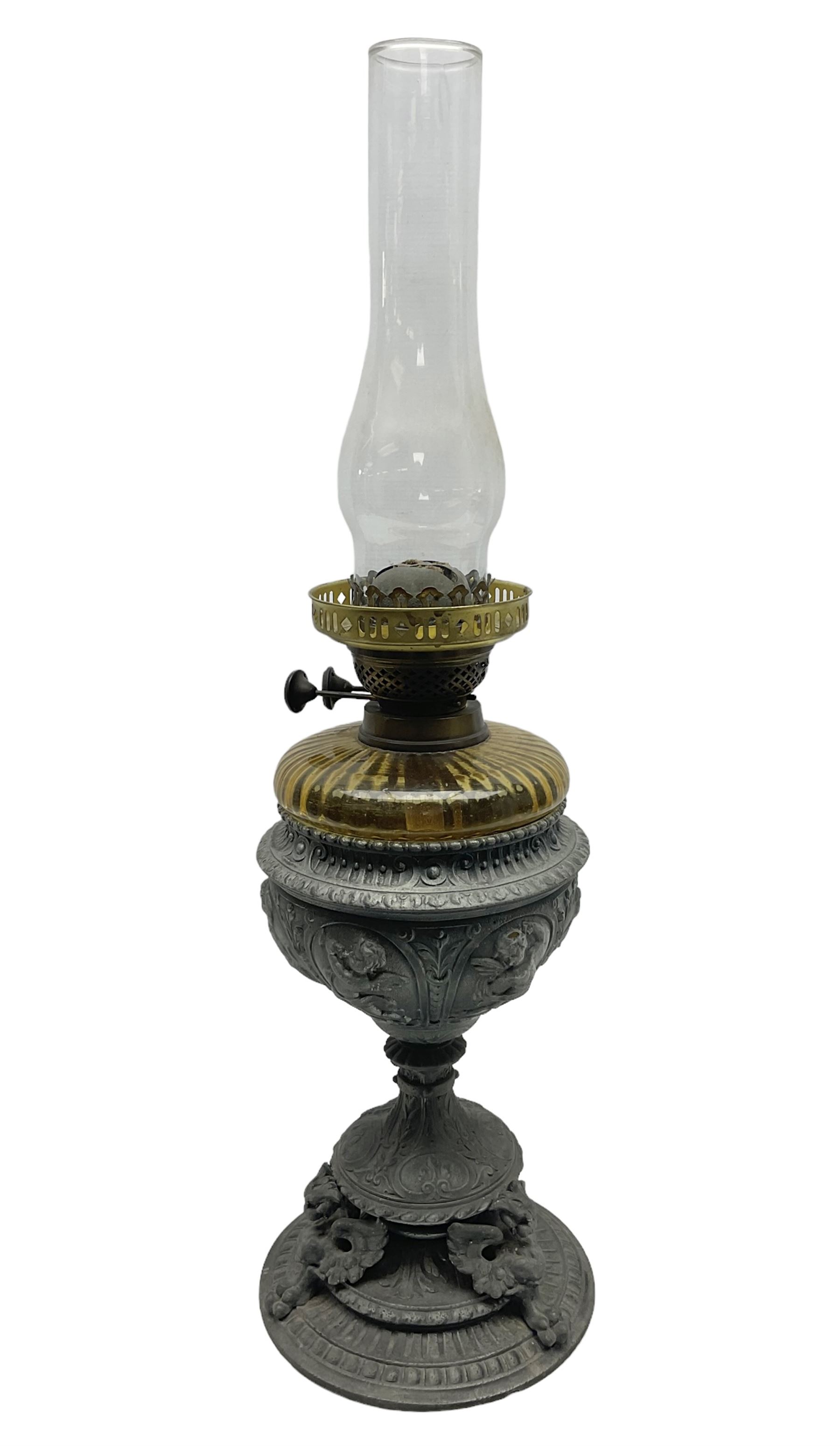 Victorian cast spelter oil lamp, decorated with cherubs and foliate scrolls, supporting a glass reservoir, burner and clear glass chimney, H62cm