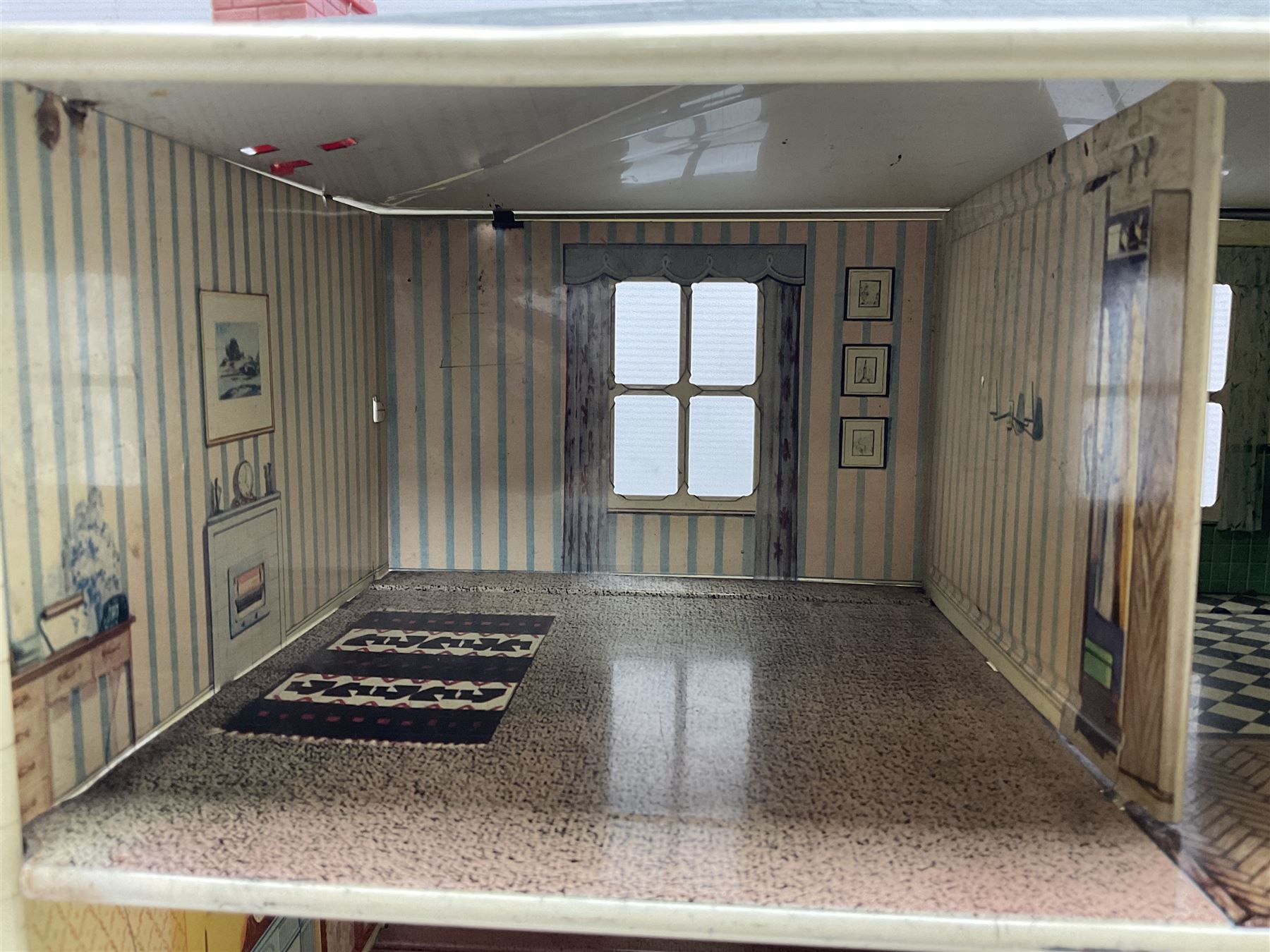 Mid-20th century Mettoy tin-plate double-fronted two-storey doll's house, the front elevation with five unglazed windows flanked by green shutters, central opening door, open back giving access to five rooms together with an attached garage, 60cm wide