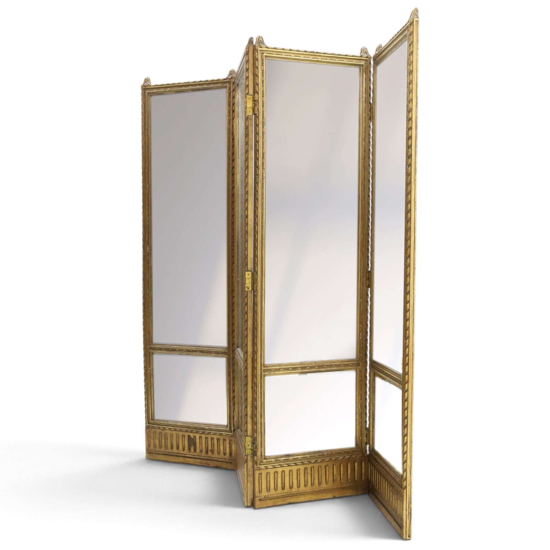 Early 20th century gilt and bevelled mirrored four panel folding screen, with two mirrors per side, flanked by beaded edges and scrolled finials, arcaded carved frieze