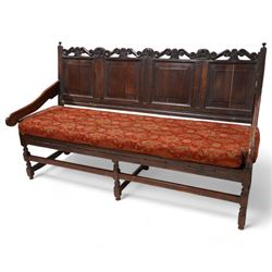Early 18th century oak hall bench or settle, the cresting rail carved with S-scrolls and crown motifs, over a quadruple panelled back with carved rail, loose seat cushion upholstered in terracotta foliate fabric, flanked by shaped arm terminals, raised on turned supports united by stretchers