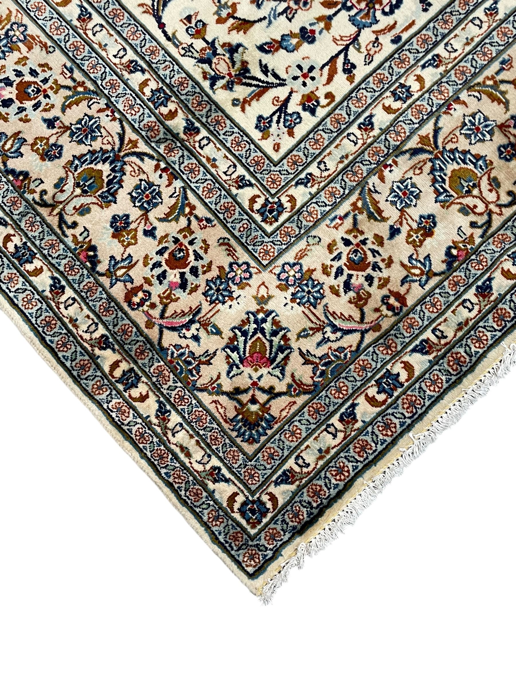 Persian Kashan ivory ground rug, decorated with curled leafy branches and palmettes, the border with scrolling design decorated with further palmettes, within floral pattern guard stripes