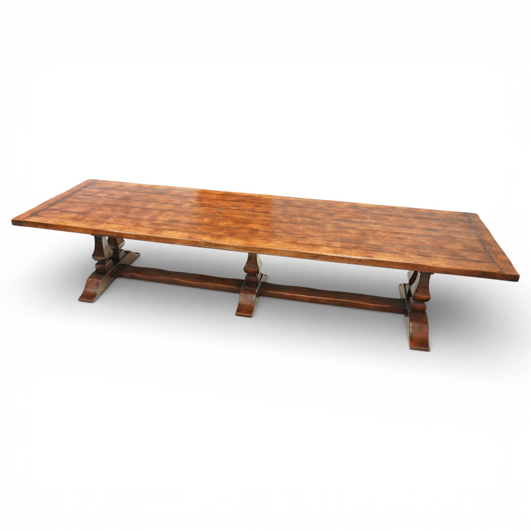 Country House 12' oak and fruitwood refectory dining table, the substantial rectangular plank top with cleated ends and chamfered edge, raised on twin trestle end square tapering and turned baluster supports with sledge feet and chamfered united by a long stretcher rail