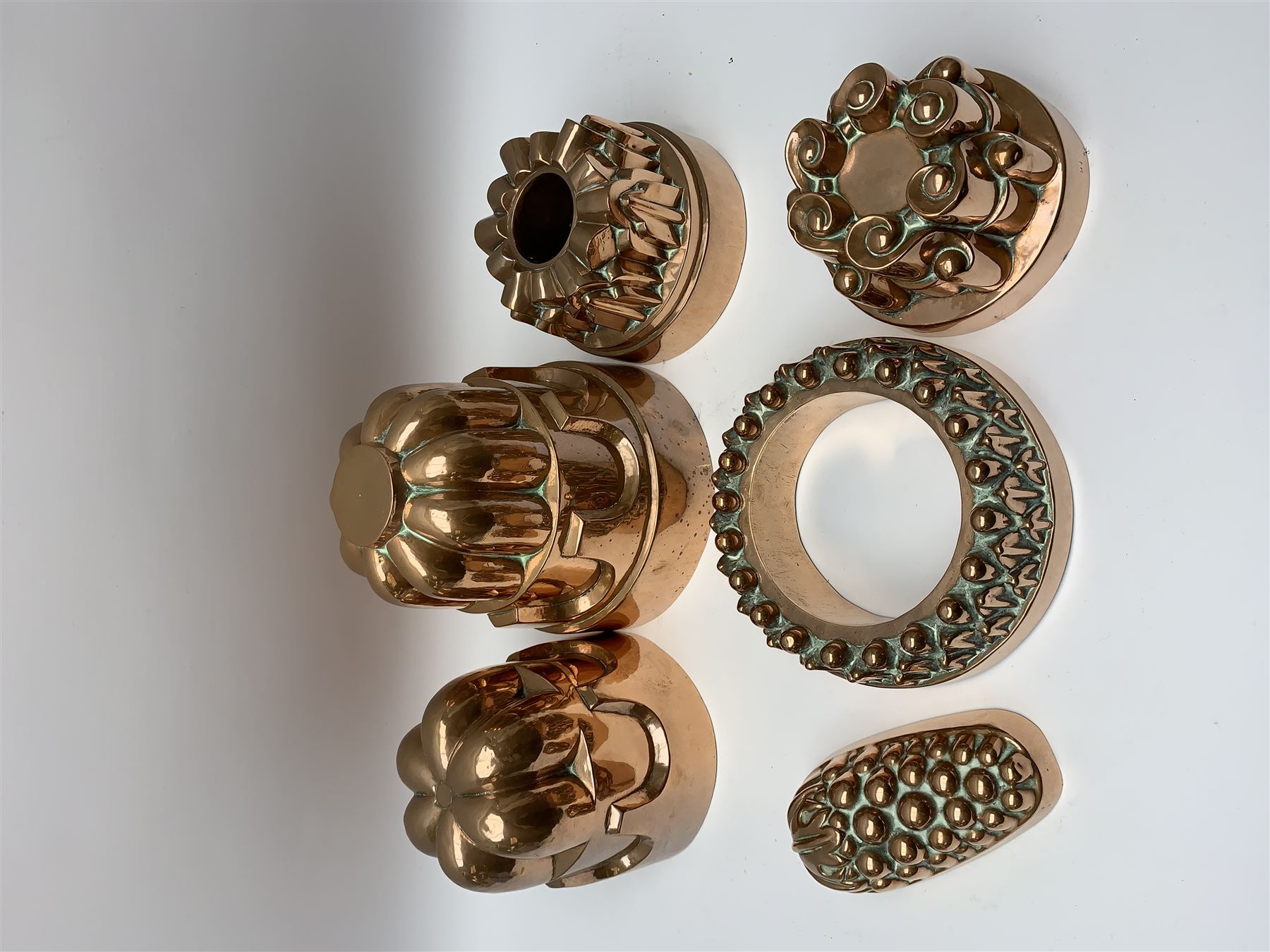 Six Victorian copper jelly moulds, five examples of castle type form, one example modelled as a bunch of grapes, largest H21cm