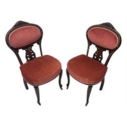 Pair of Edwardian inlaid rosewood salon chairs, upholstered in dusky pink fabric with gimp trim, oval backrest with carved crest rail with central shell motif and pierced splat, on cabriole supports terminating in castors