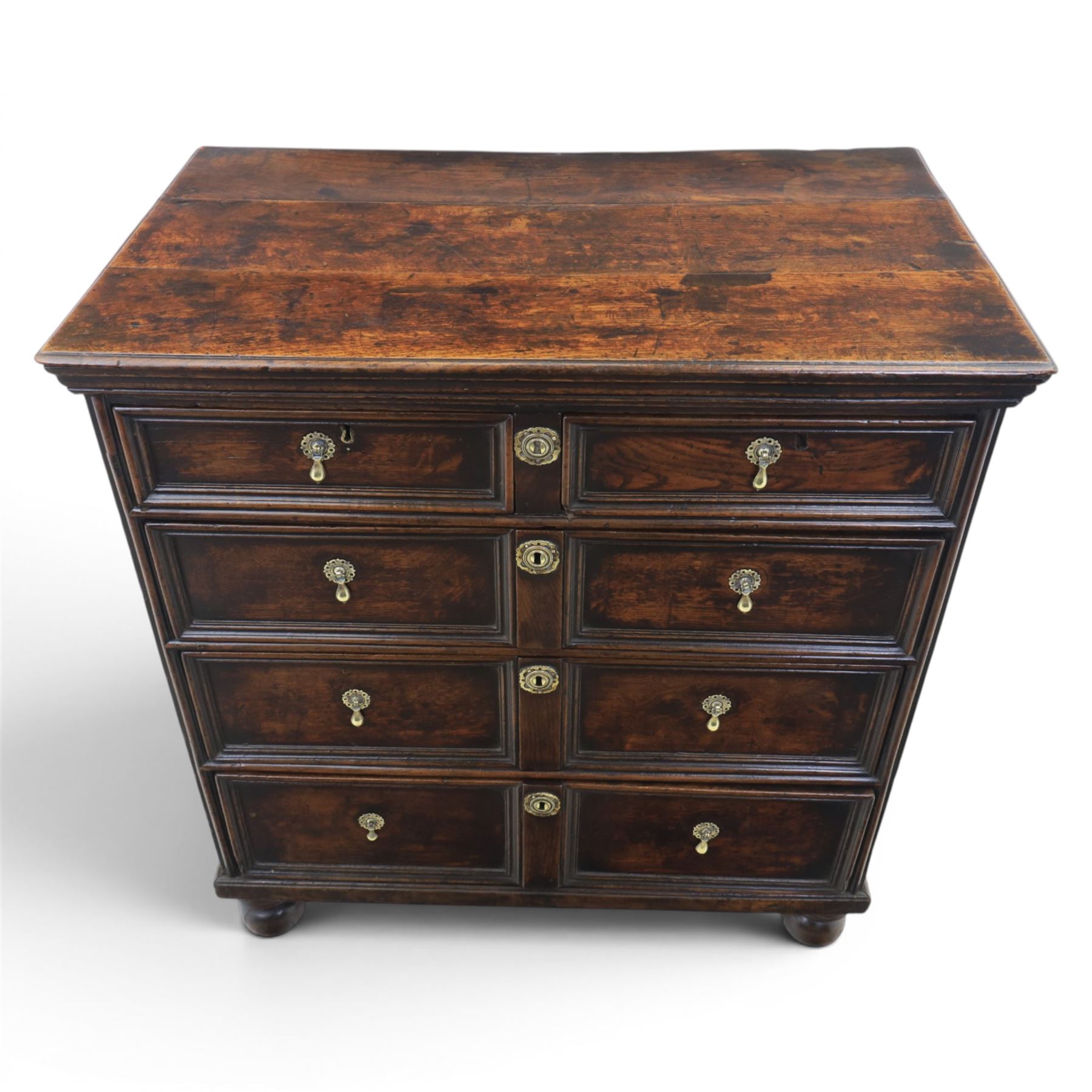 Late 17th century moulded front oak chest of drawers, rectangular plank top. above two banks of four graduated drawers, central escutcheons and drop handles, on squat bun feet