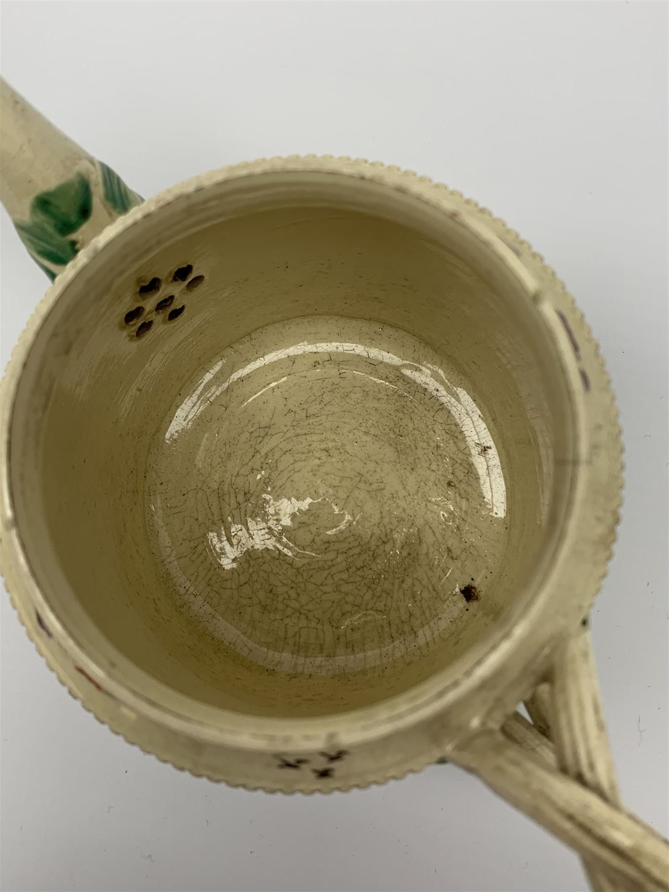 18th century creamware teapot, probably Leeds, with reeded entwined handle and floral finial to the cover, the body with hand painted polychrome decoration of figure to one side, and floral spray to the other, collectors paper label beneath inscribed Leeds Pottery, H11.5cm