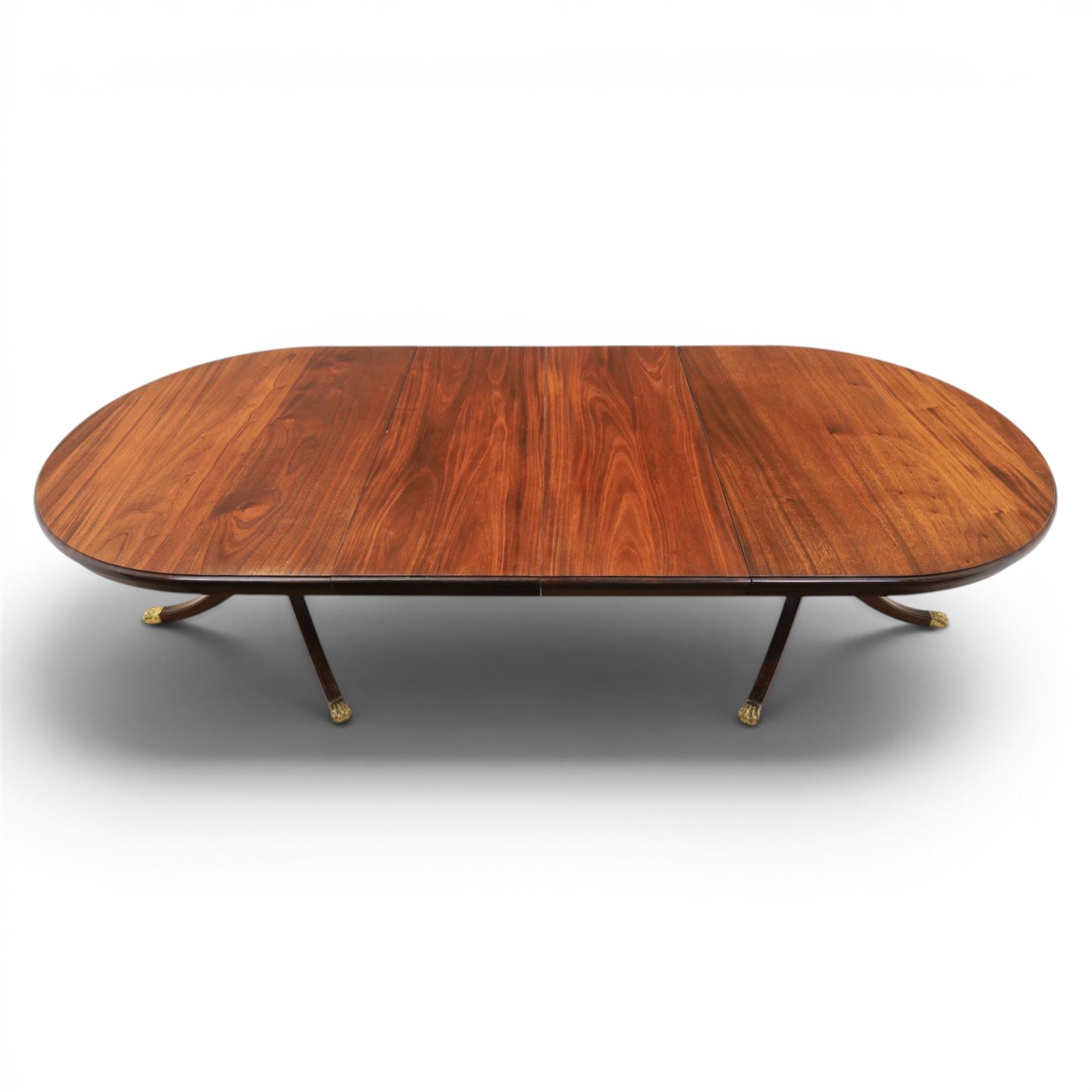 Regency design mahogany extending twin pedestal dining table with two additional leaves, raised on splayed supports terminating brass paw feet
Extends to 268cm